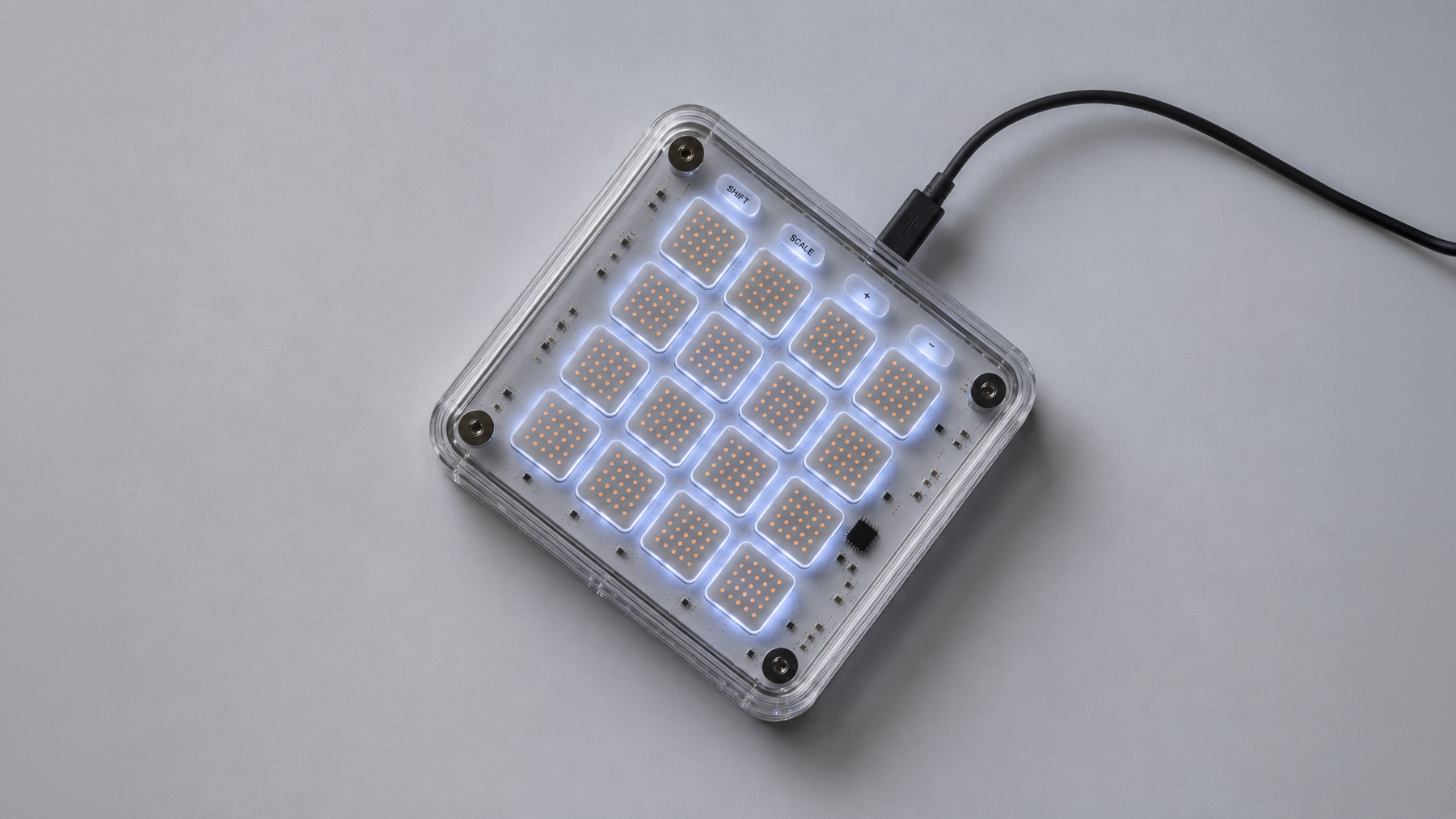 A haptic capable electronic music controller with illuminated grid pads, some labeled shift and scale, connected via USB.