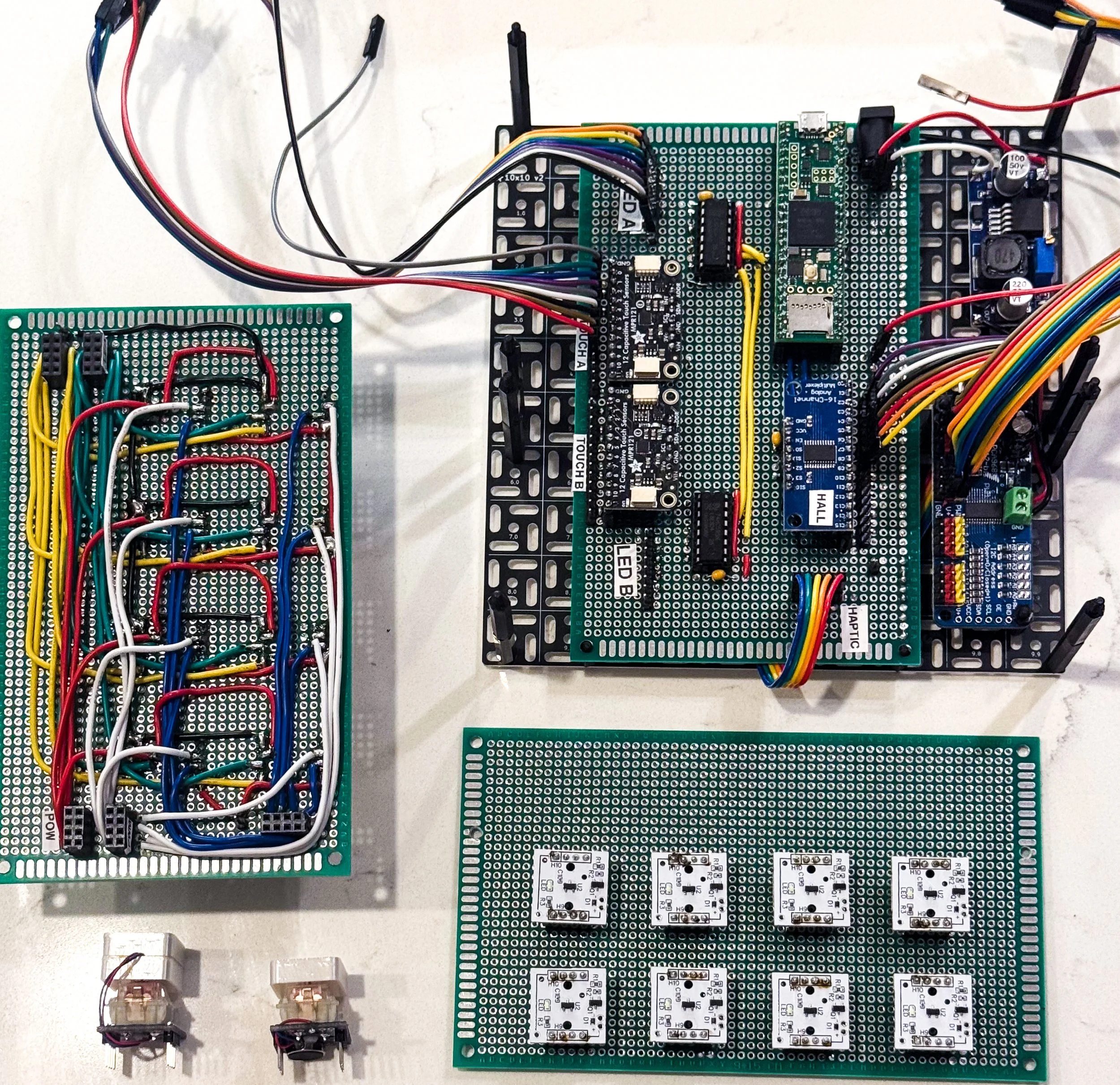 Multiple electronic circuit boards with various wires, microchips, and components on a white surface.