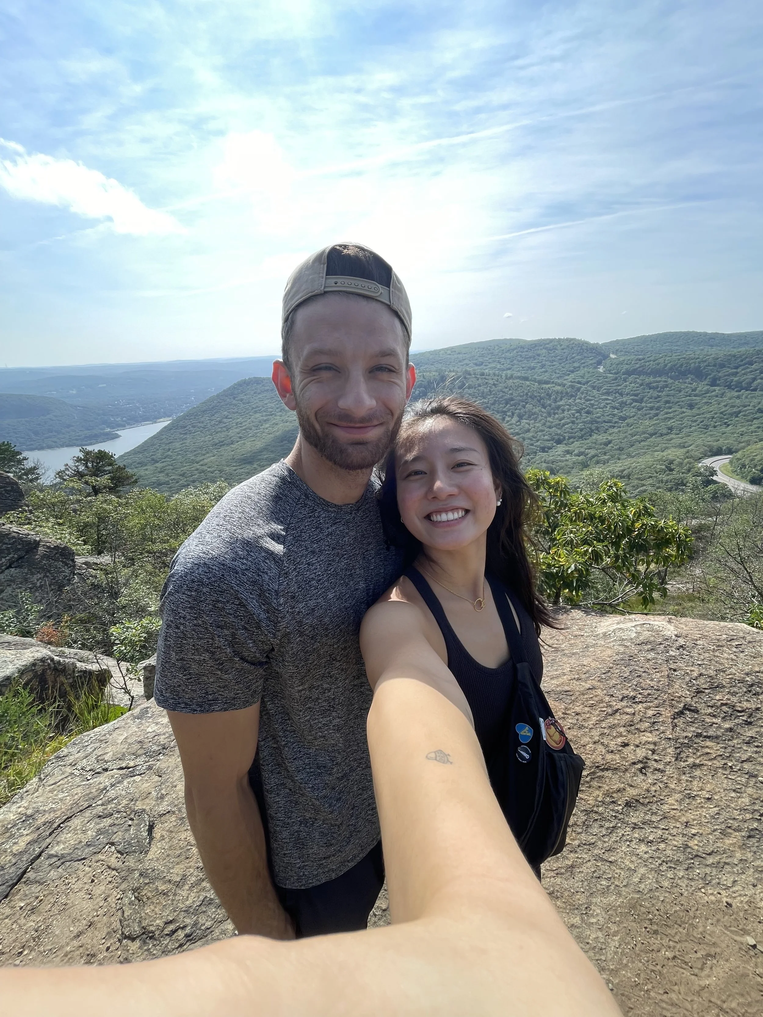 The business owners JJ and Angelina Giannitsis standing on top of a mountain overlooking a valley.