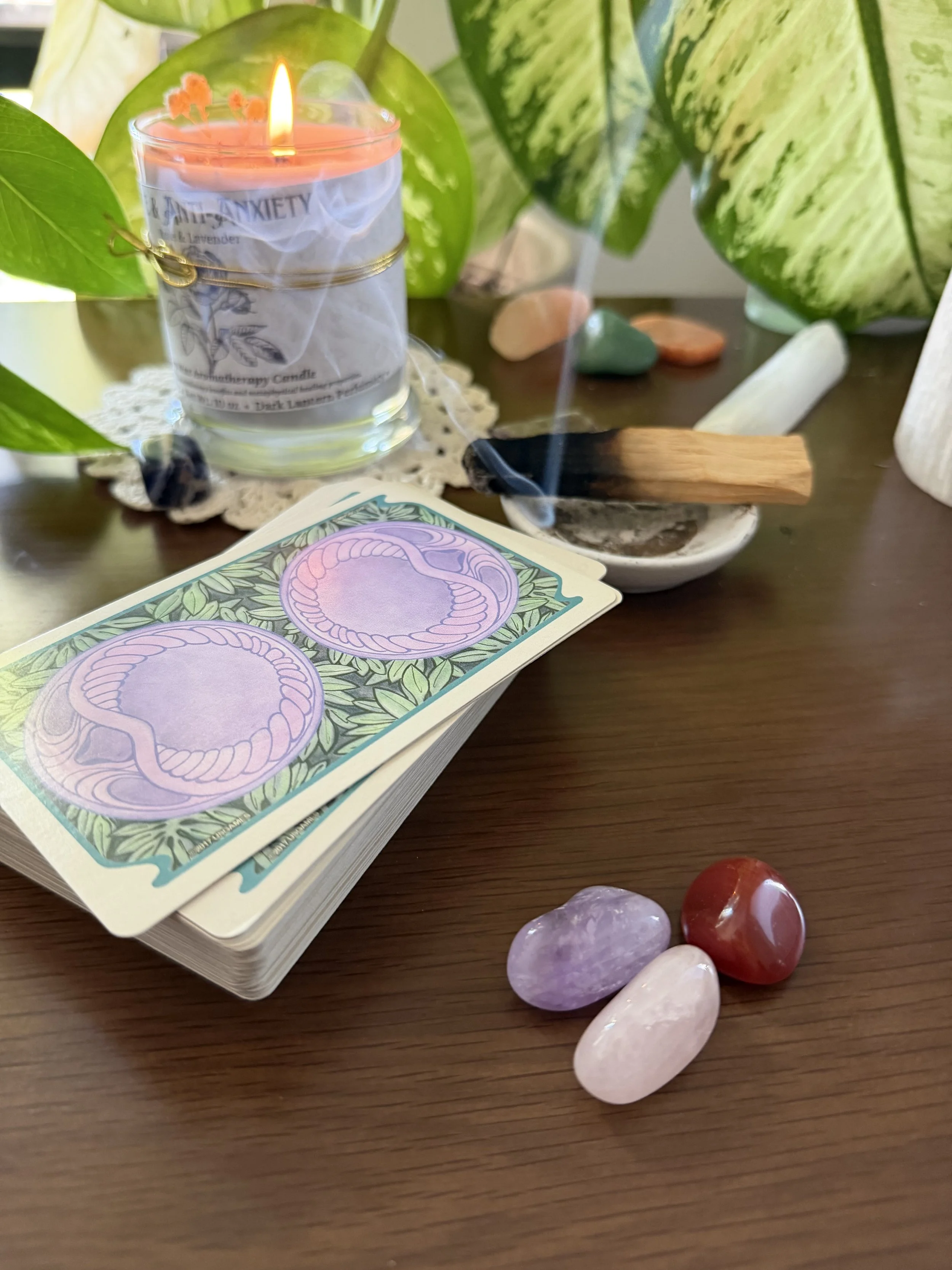 A lavender candle surrounded by crystals and tarot cards, showcasing mindfulness and somatic therapy tools.