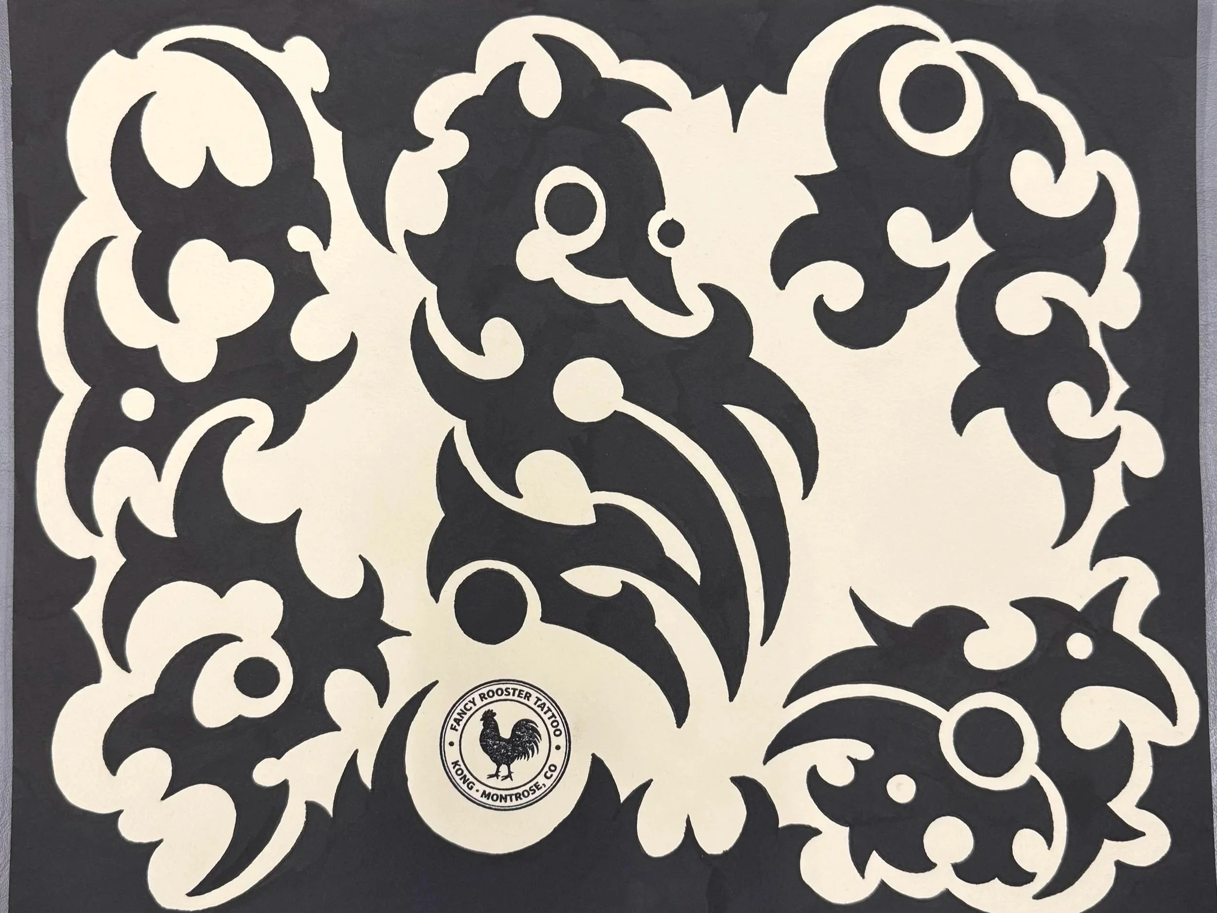 Black and white decorative sticker sheet with ornate swirling patterns and a circular logo featuring a rooster at the bottom center, with text indicating 'Fancy Rooster Tattoo, Kong, Montrose, CO'.