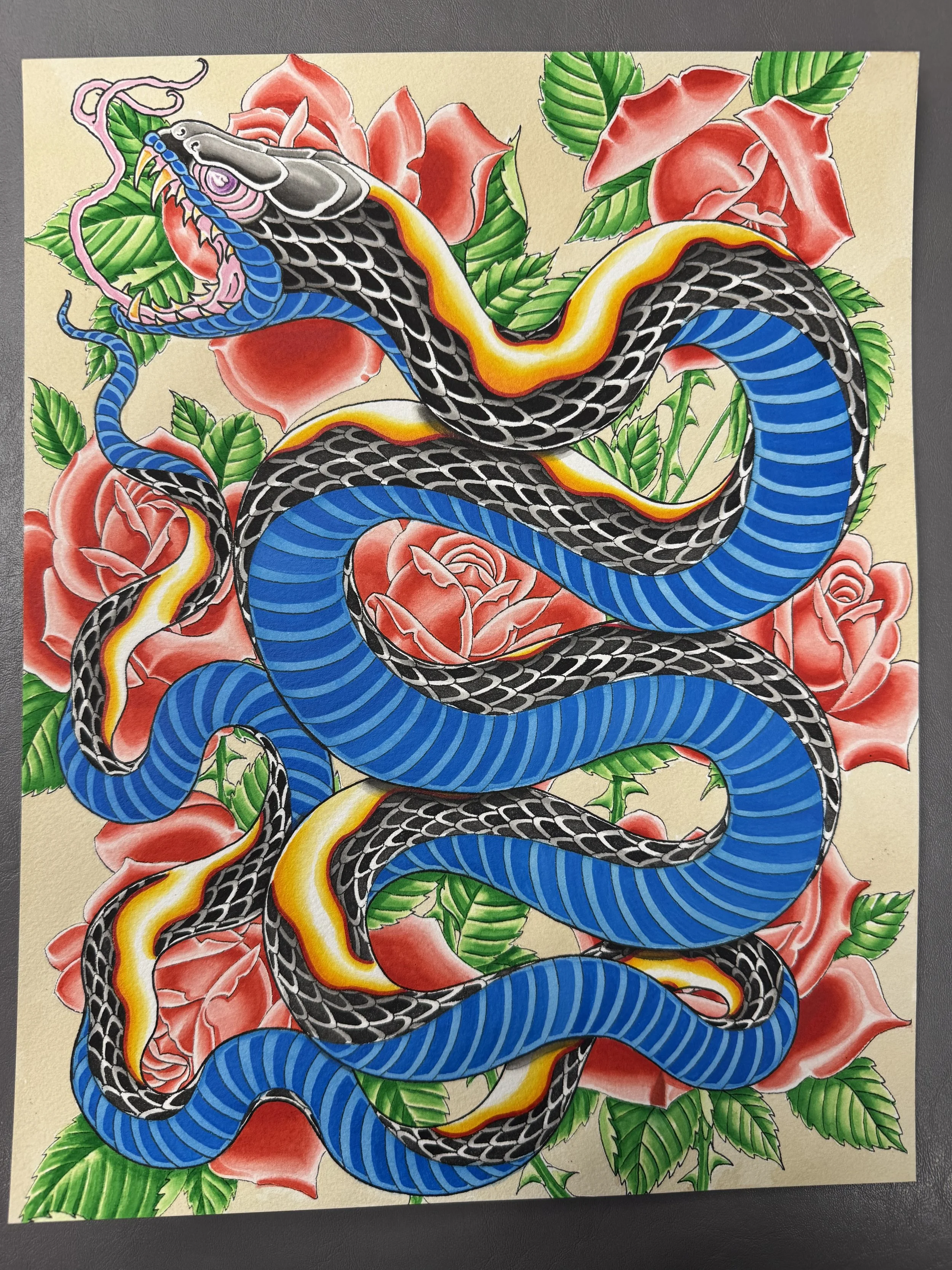 A vibrant illustration of a snake with black, blue, yellow, and red patterns, intertwined among green leaves and large pink roses on a beige background.