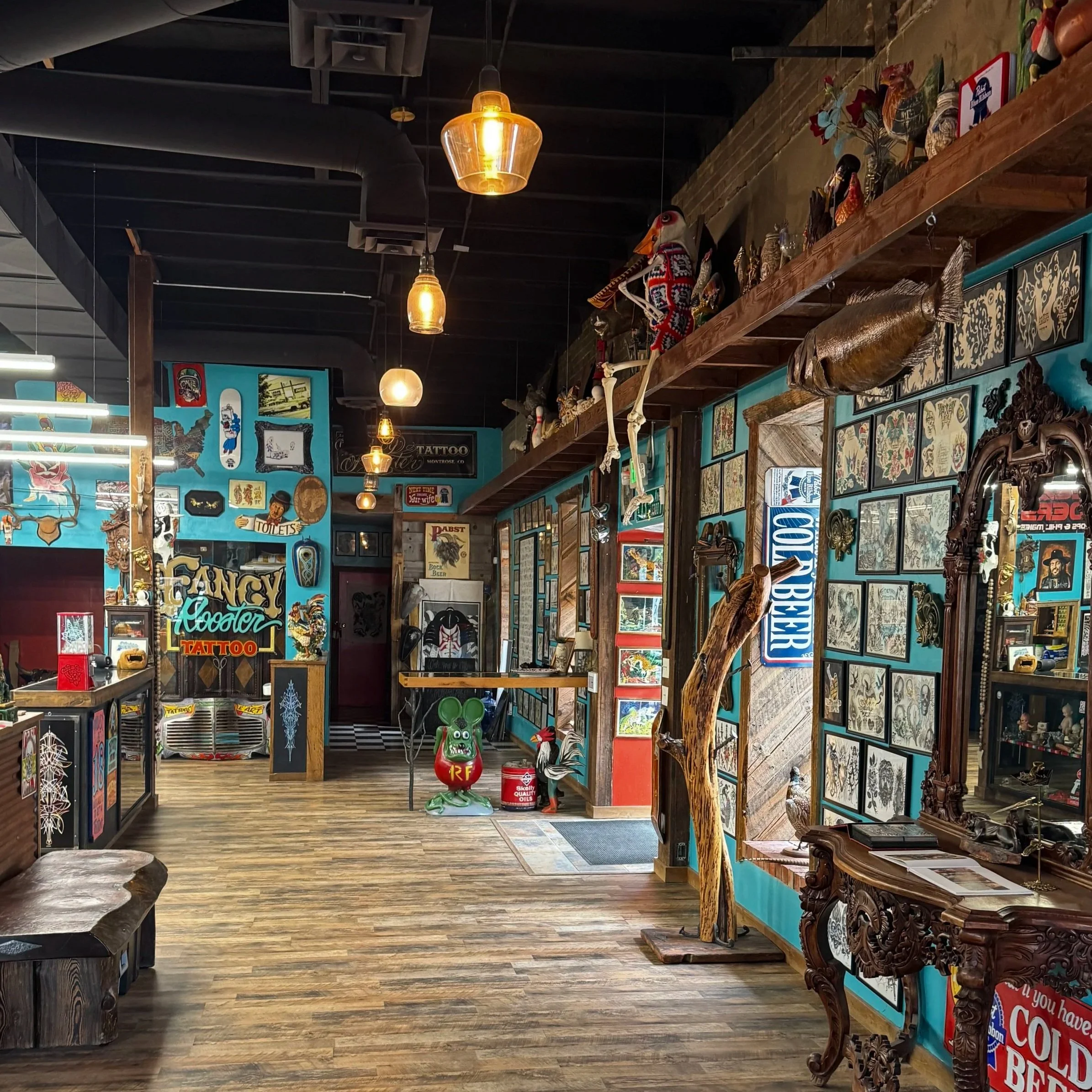 Interior of a store decorated with vintage signs, artwork, and figurines, with hanging pendant lights and wood accents.