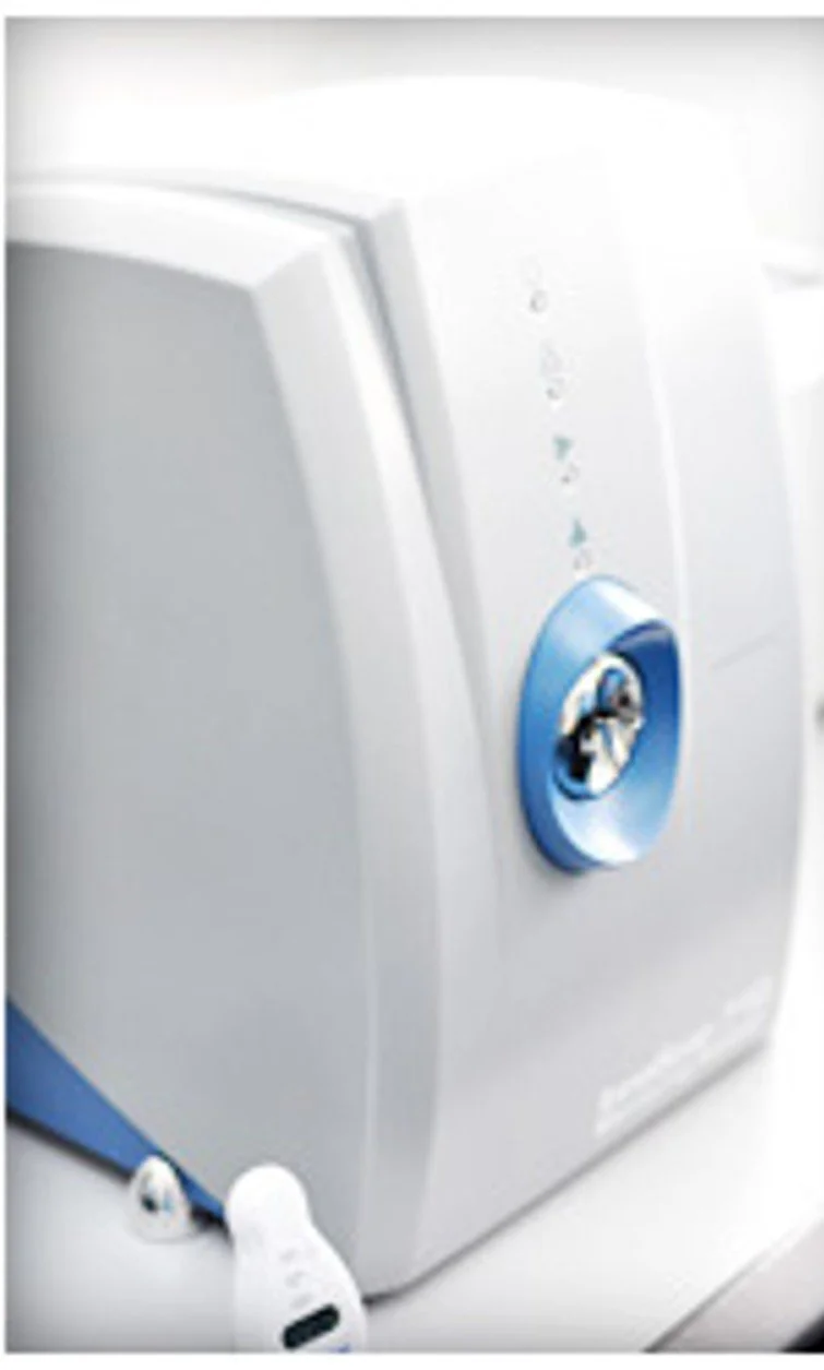 Close-up of a white medical or laboratory machine with a blue control dial and indicator lights.