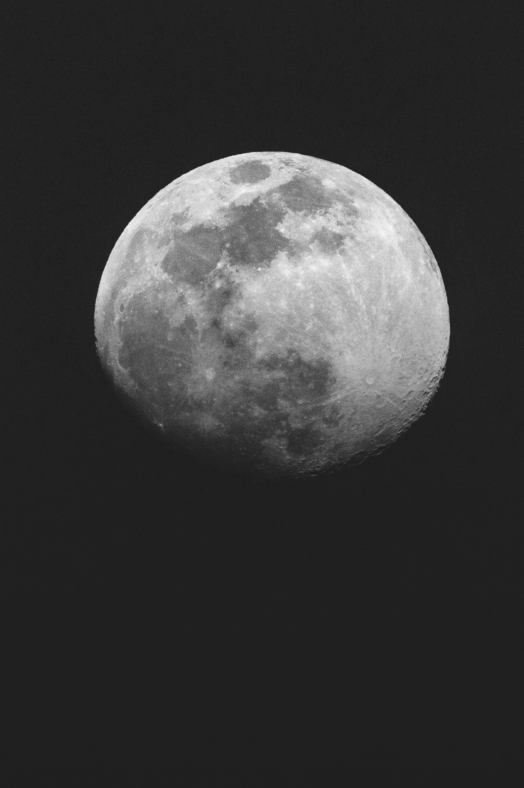 Imagen de la luna llena en un cielo oscuro, en escala de grises.
