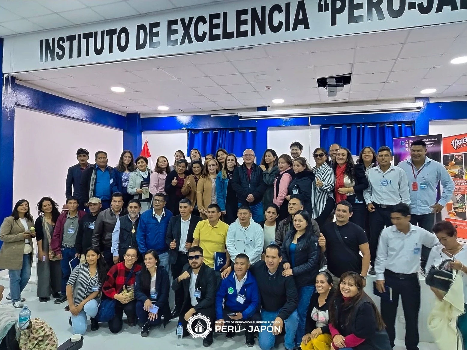 Grupo de personas en una conferencia o evento académico en un aula o salón de clases, con un cartel que dice 'Instituto de Excelencia Perú-Japón' en el fondo.