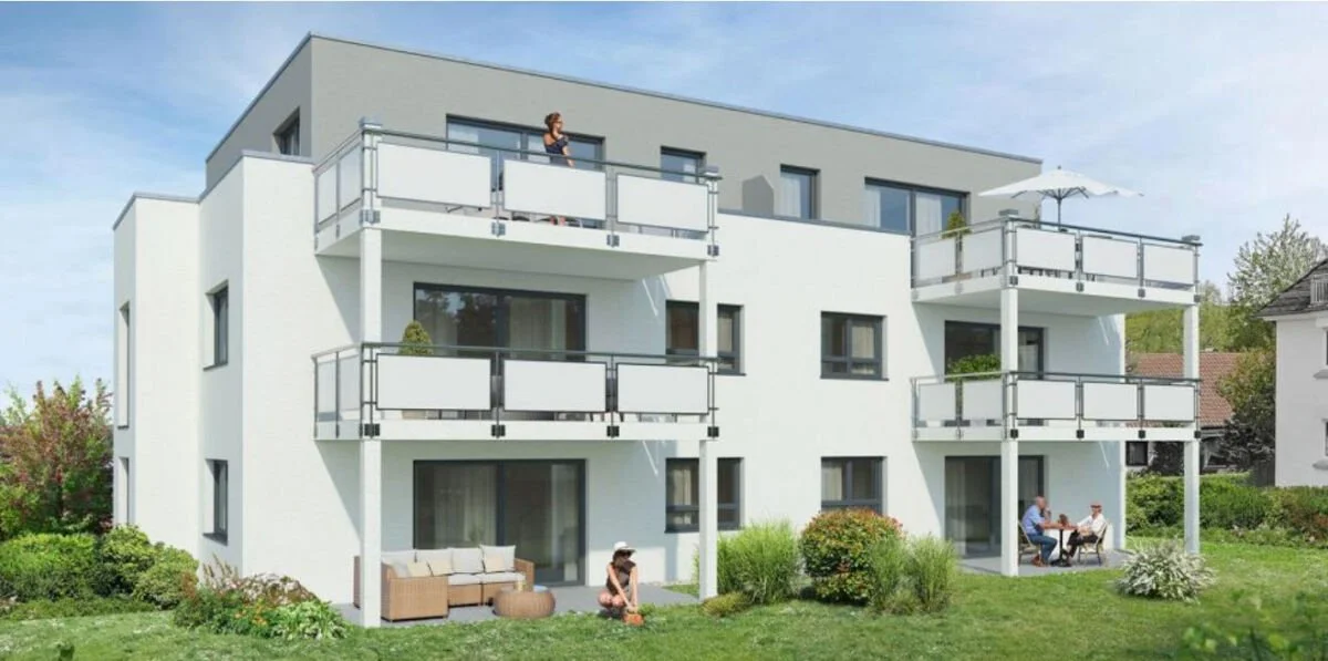 Ein moderates, weißes Mehrfamilienhaus mit mehreren Balkonen, auf denen Menschen entspannt sitzen oder spazieren gehen, umgeben von grünem Garten unter blauem Himmel.