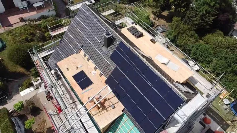 Dach eines Gebäudes mit Solarpanelen, umgeben von Gerüsten.