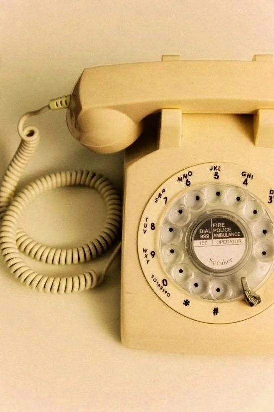 A vintage cream-colored rotary phone on a white surface.
