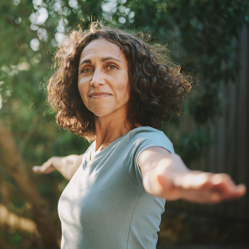 Frau mittleren Alters macht Yoga in der Natur - Bewegung in den Wechseljahren