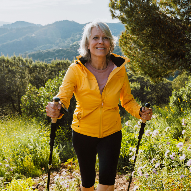 Frau in den Wechseljahren macht Nordic Walking in der Natur und sorgt für Ausgleich