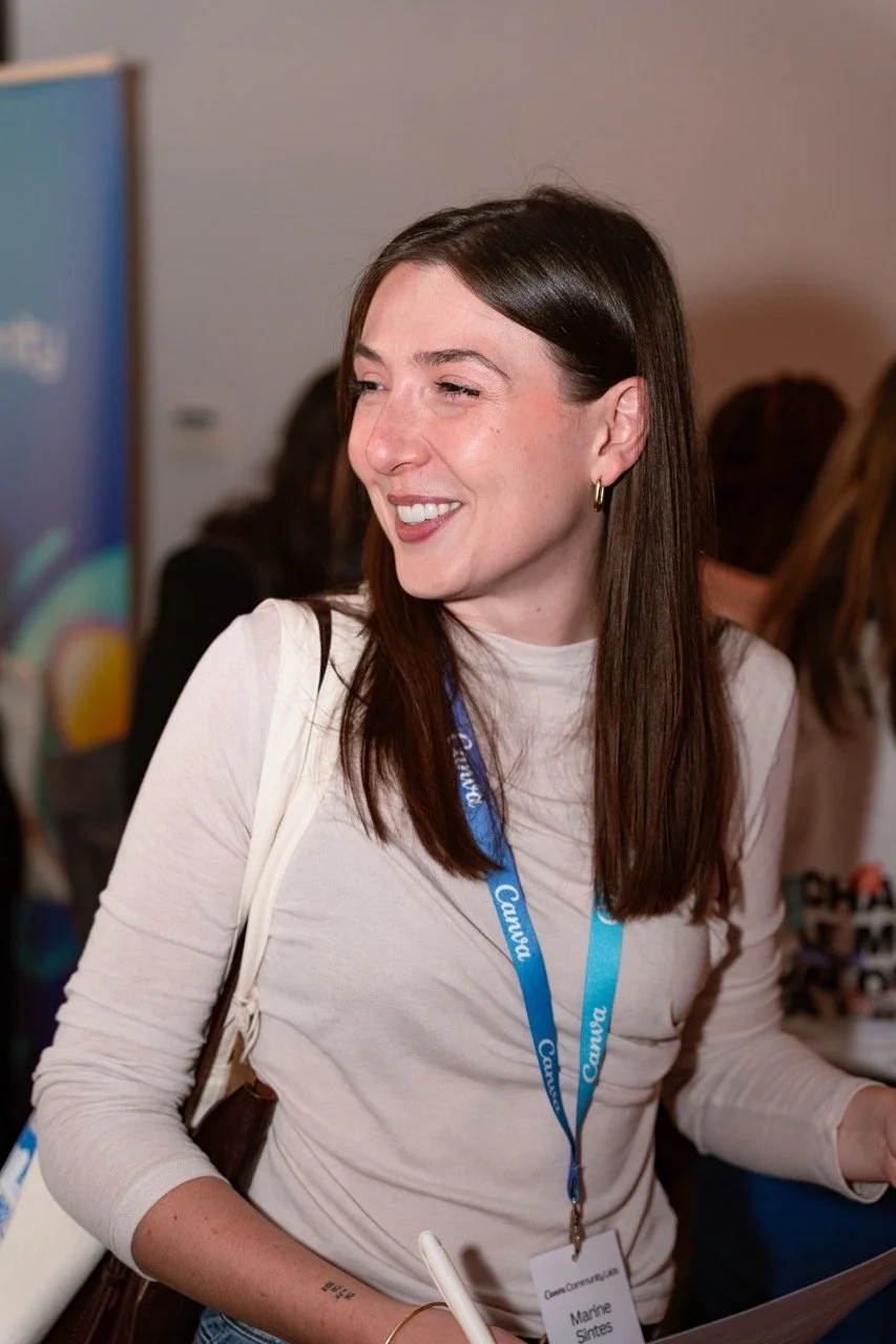 Une femme souriante portant un badge bleu à une conférence.