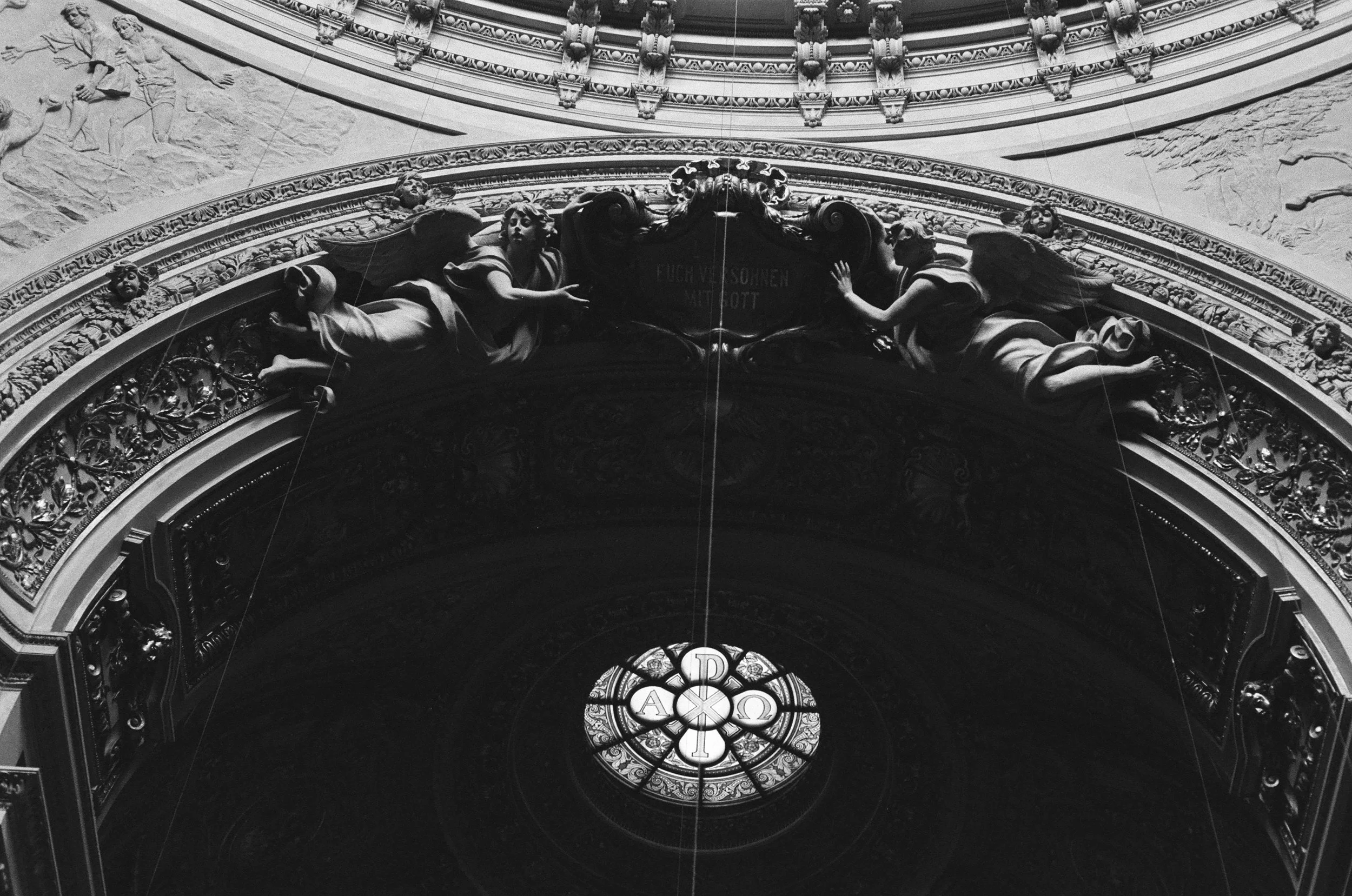 Historic church interior with angel sculptures and stained glass window, black and white fine art photography