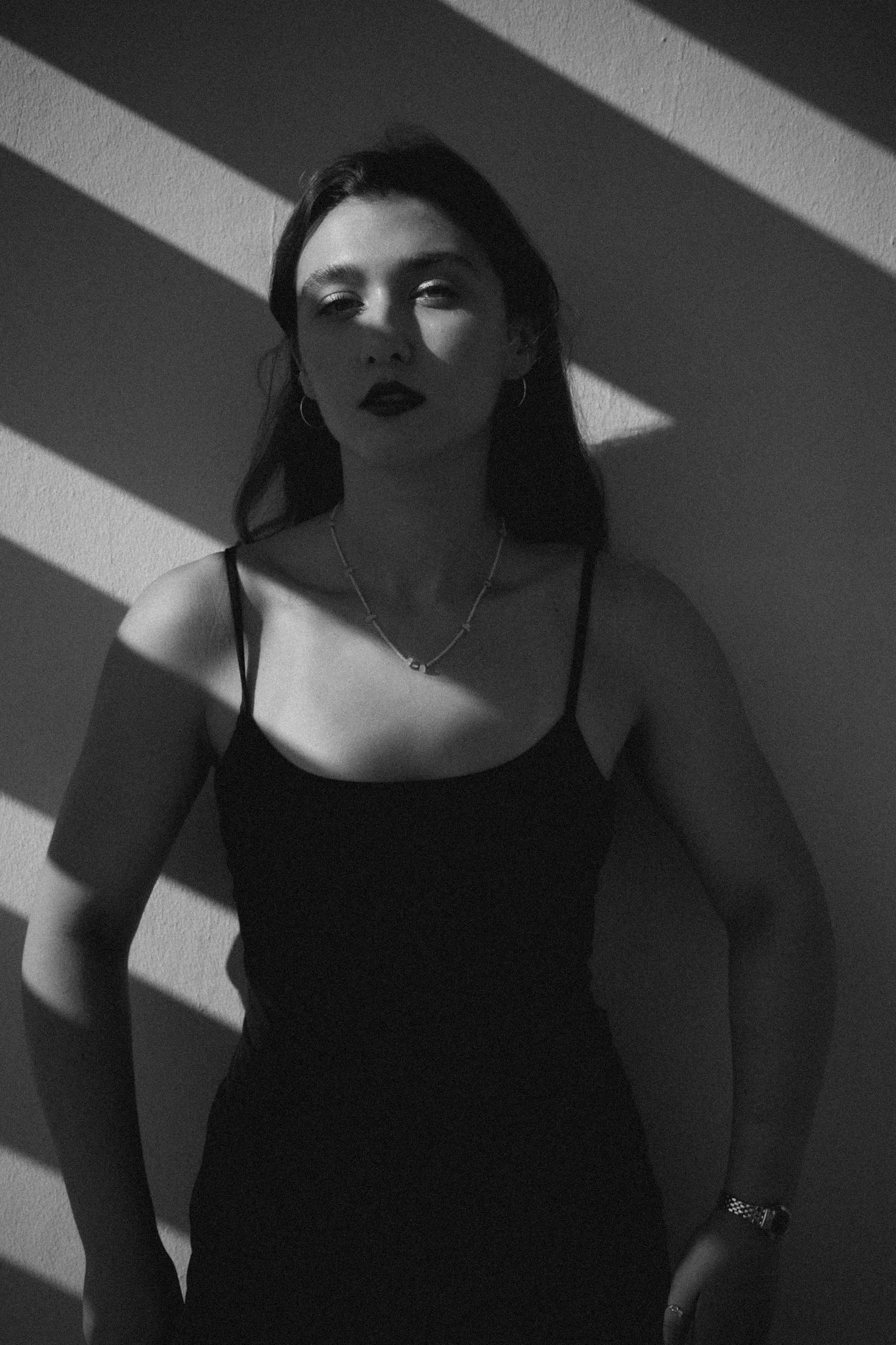 Black and white portrait of a woman illuminated by dramatic shadows and natural light.
