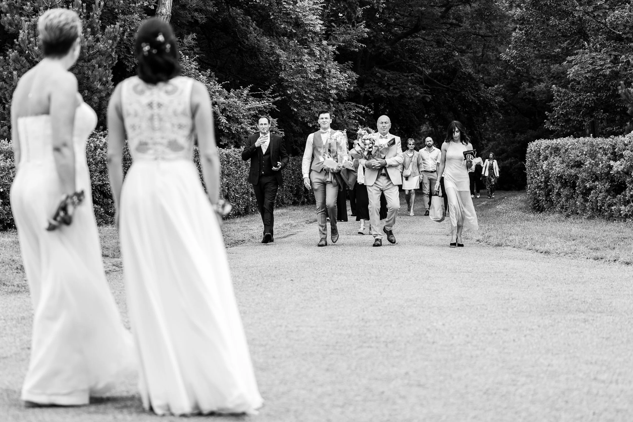 Groupe de personnes se promenant dans un parc, certains en costumes, lors d'une cérémonie ou d'un événement social.