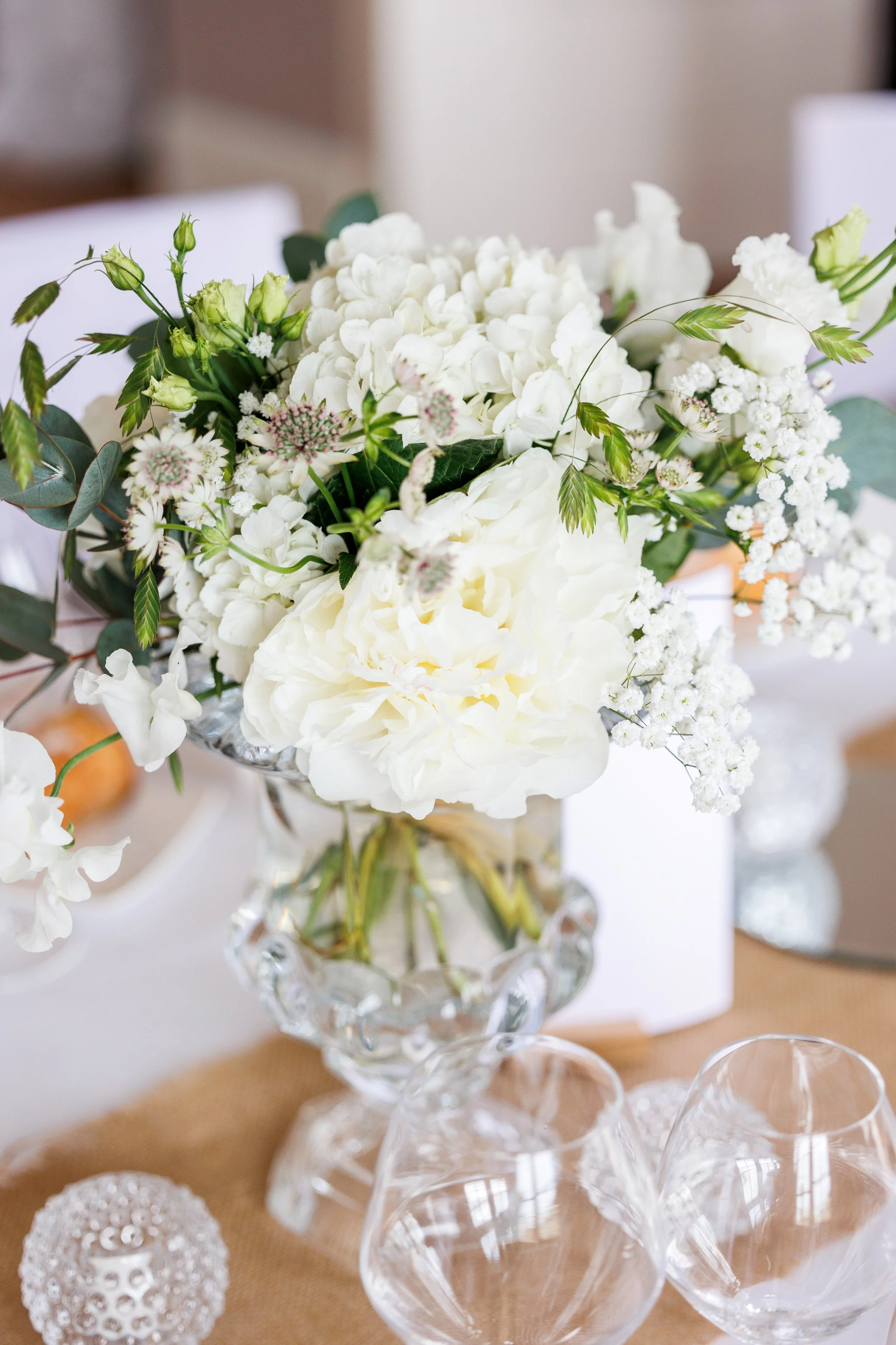 Bouquet de fleurs blanches dans un vase en cristal placé sur une table en tissu