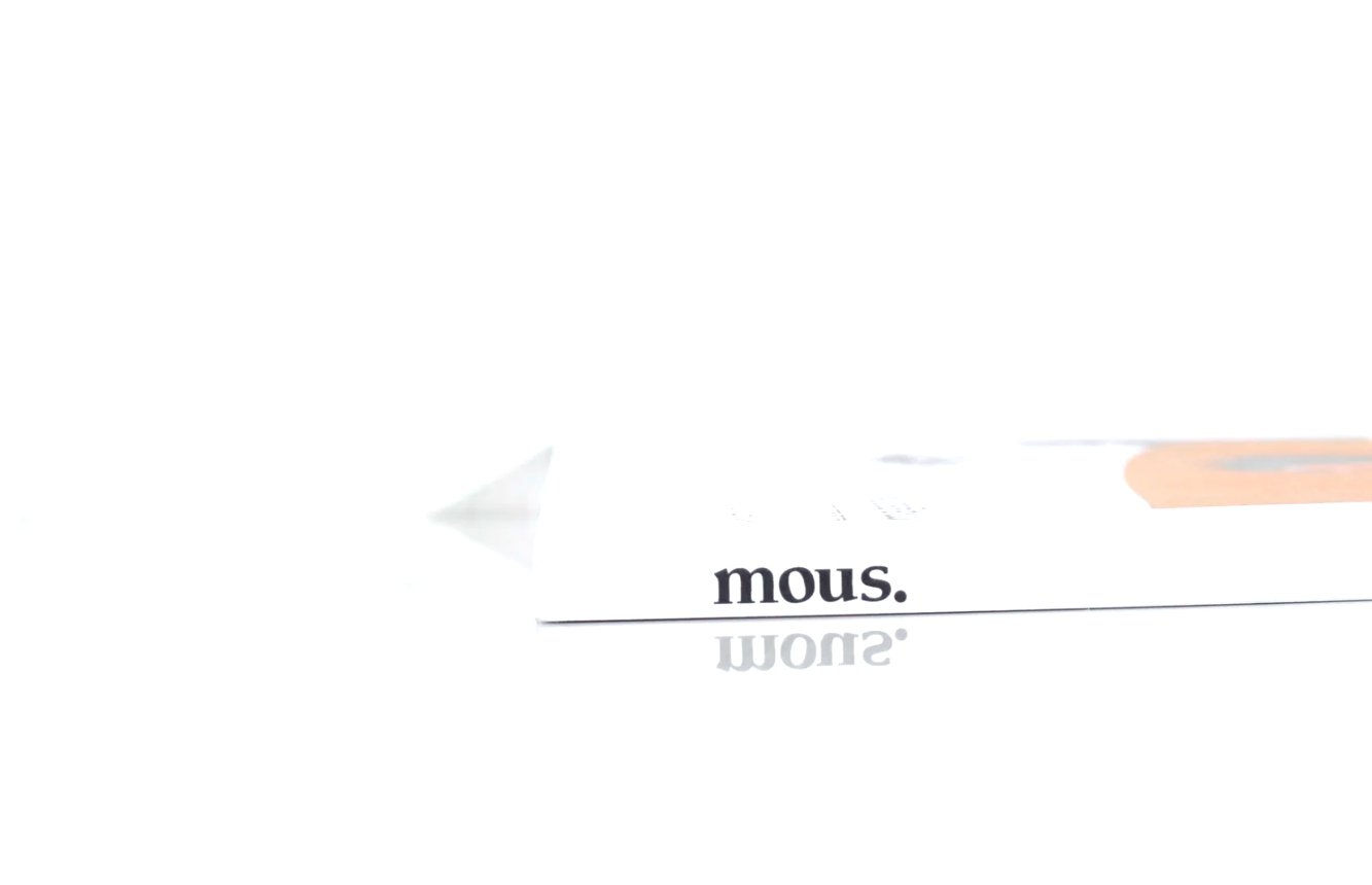 Close-up of a white box with the word 'mous.' printed on it, reflecting on a white surface.