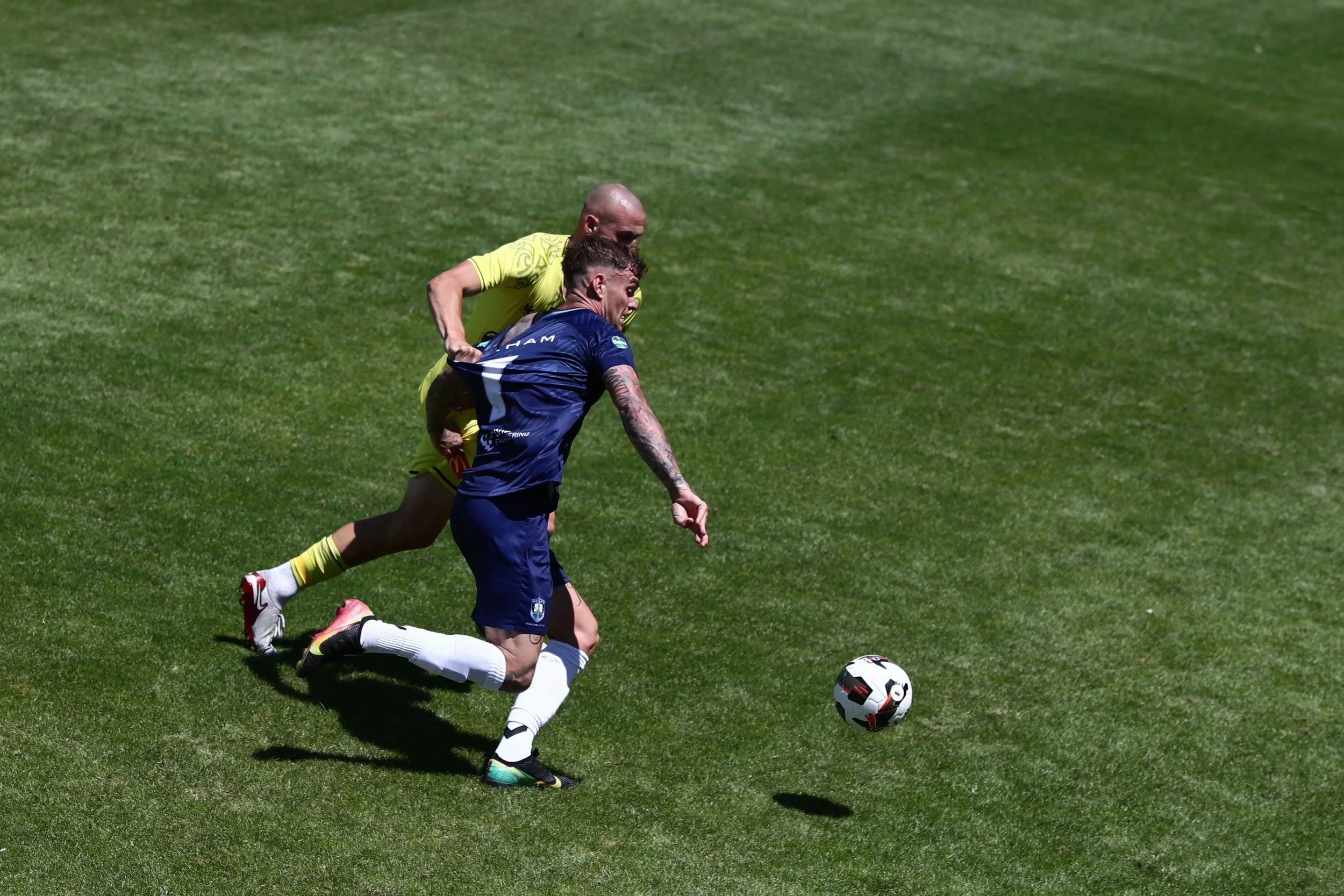 Soccer players competing for the ball on a green field.