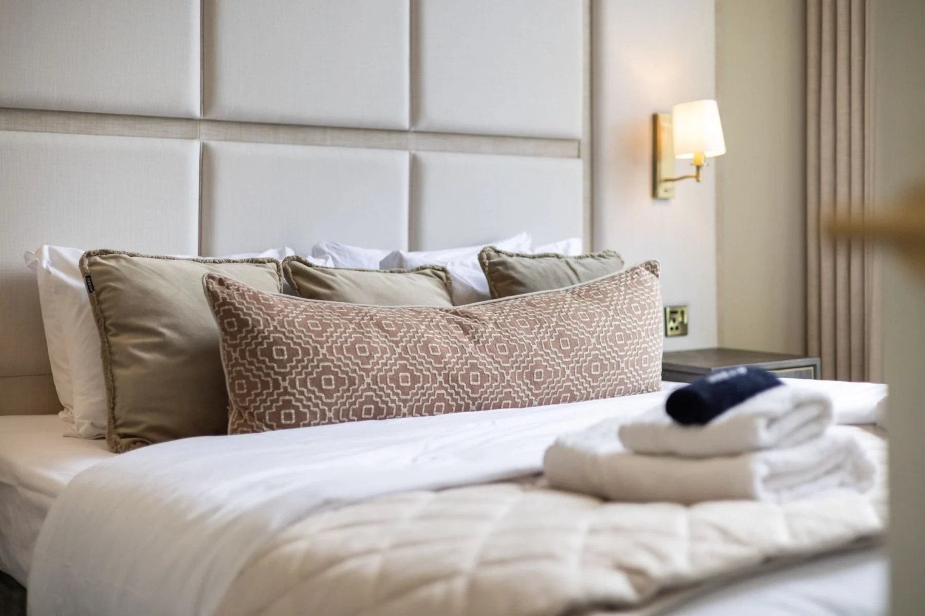 Principal bedroom with full-height upholstered wall panels and brass wall light at West Regent Street, Glasgow, by SANNA Design Studio