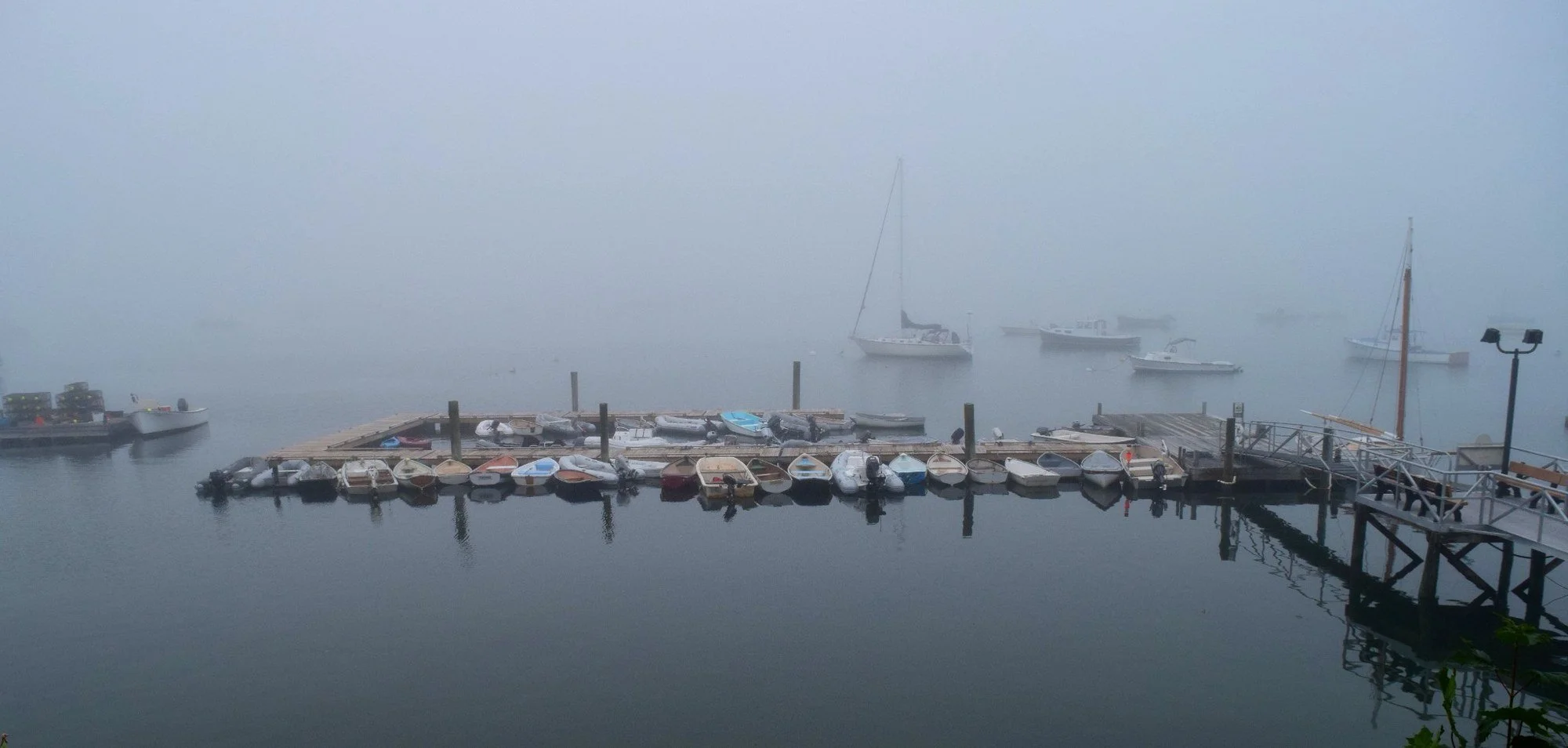 Boats and docks in Southwest Harbor on Mount Desert Island, Maine, nearly hidden by thick fog over the water.