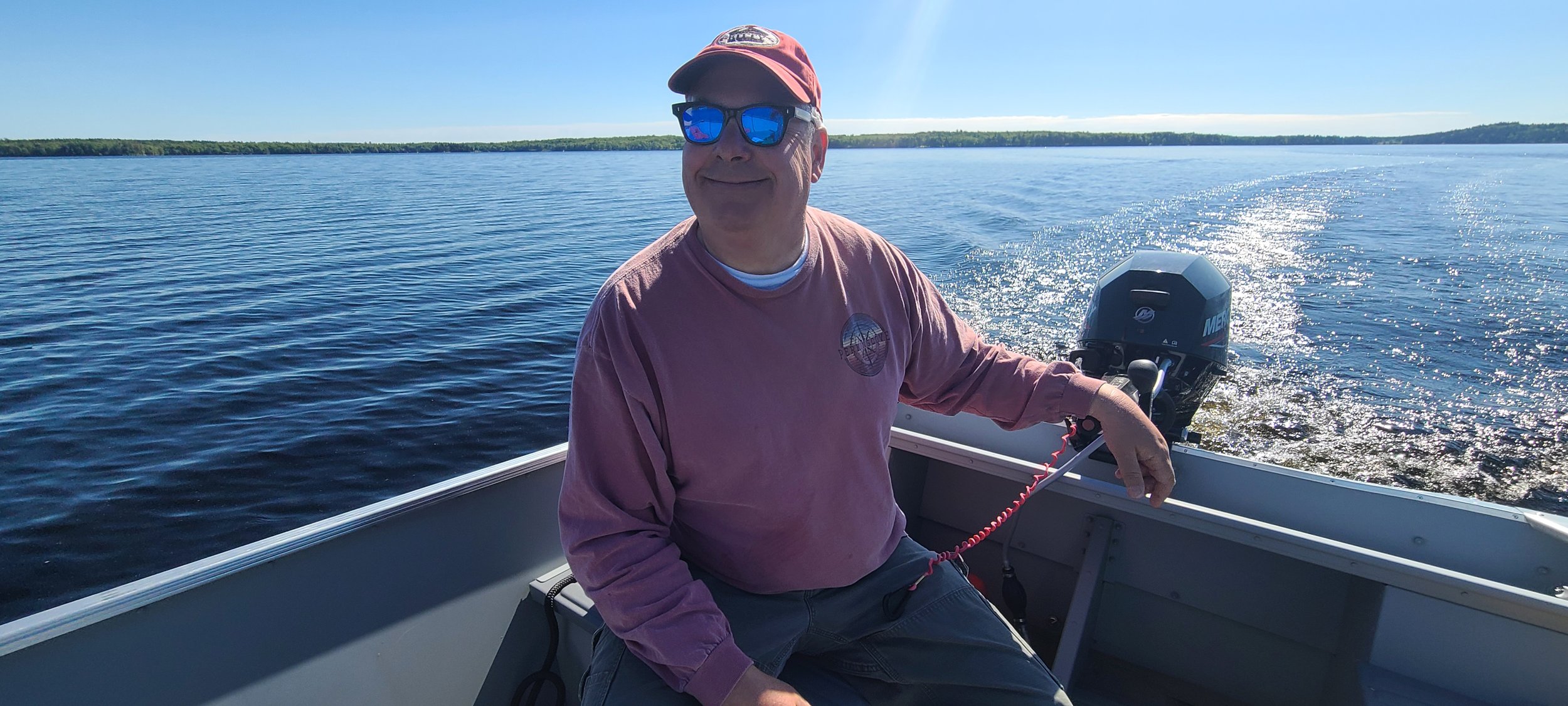 Tim Billings, creator of My Acadia, My Maine, sitting in a small boat on the water off Mount Desert Island