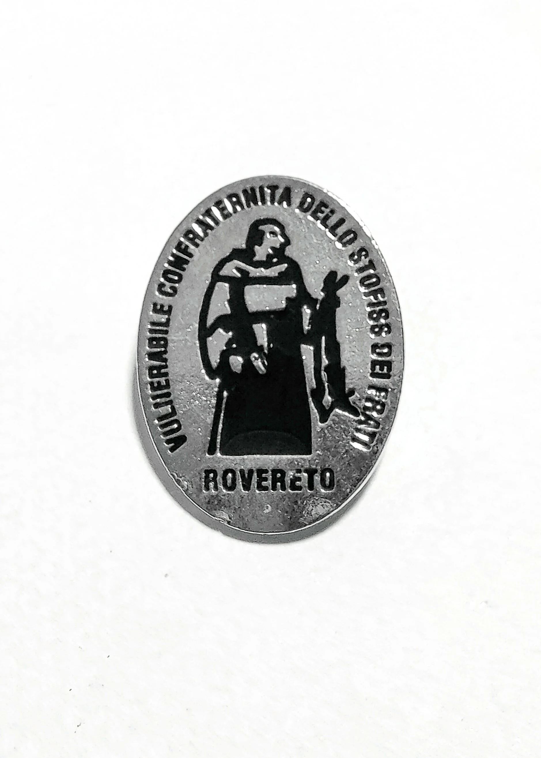Medalla de color plateado que tiene una figura de una mujer con un niño, usando una corona de laureles, y rodeada con inscripciones en español que dicen 'Enrique Fernández Anarita Della Storia, Rovereto'.