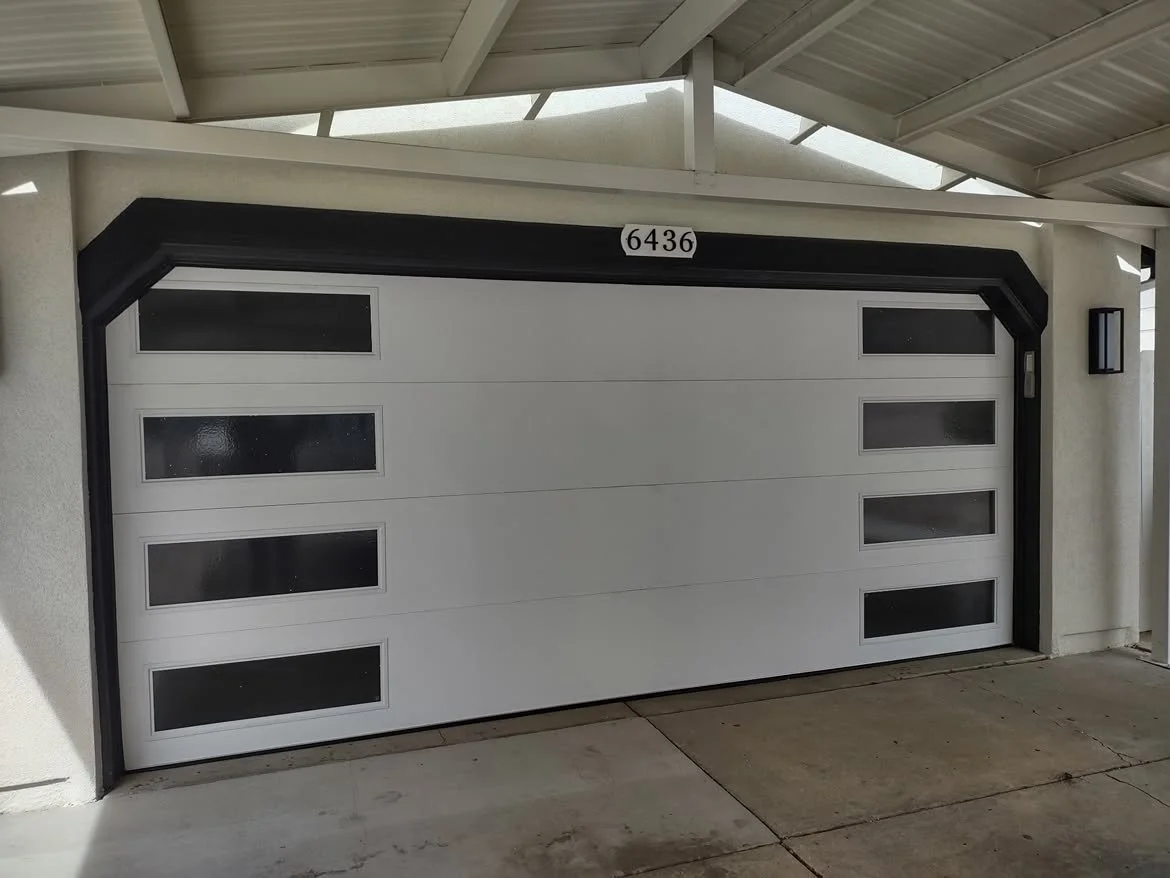 White garage door with five small rectangular windows, framed by black trim, and house number 6436 above.