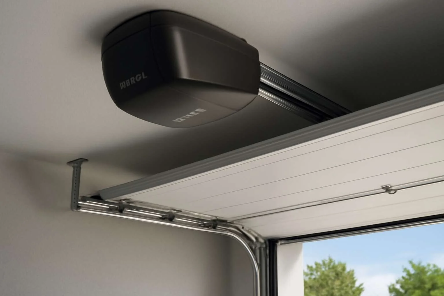 Close-up of a garage door opener mounted on the ceiling with a partially open garage door showing trees outside.