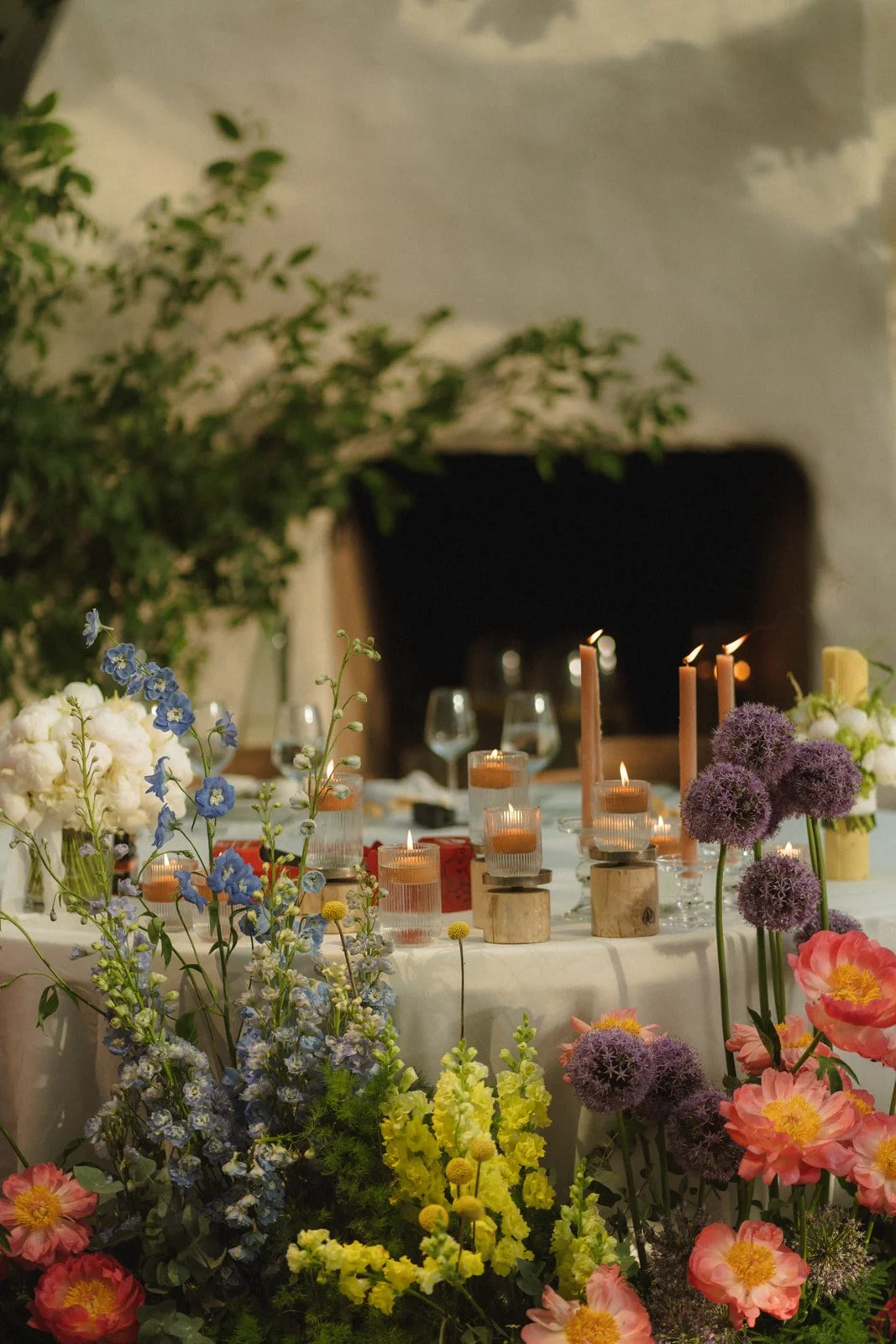 A decorated table with candles and colorful flowers, set for a celebration or event in a cozy indoor setting.