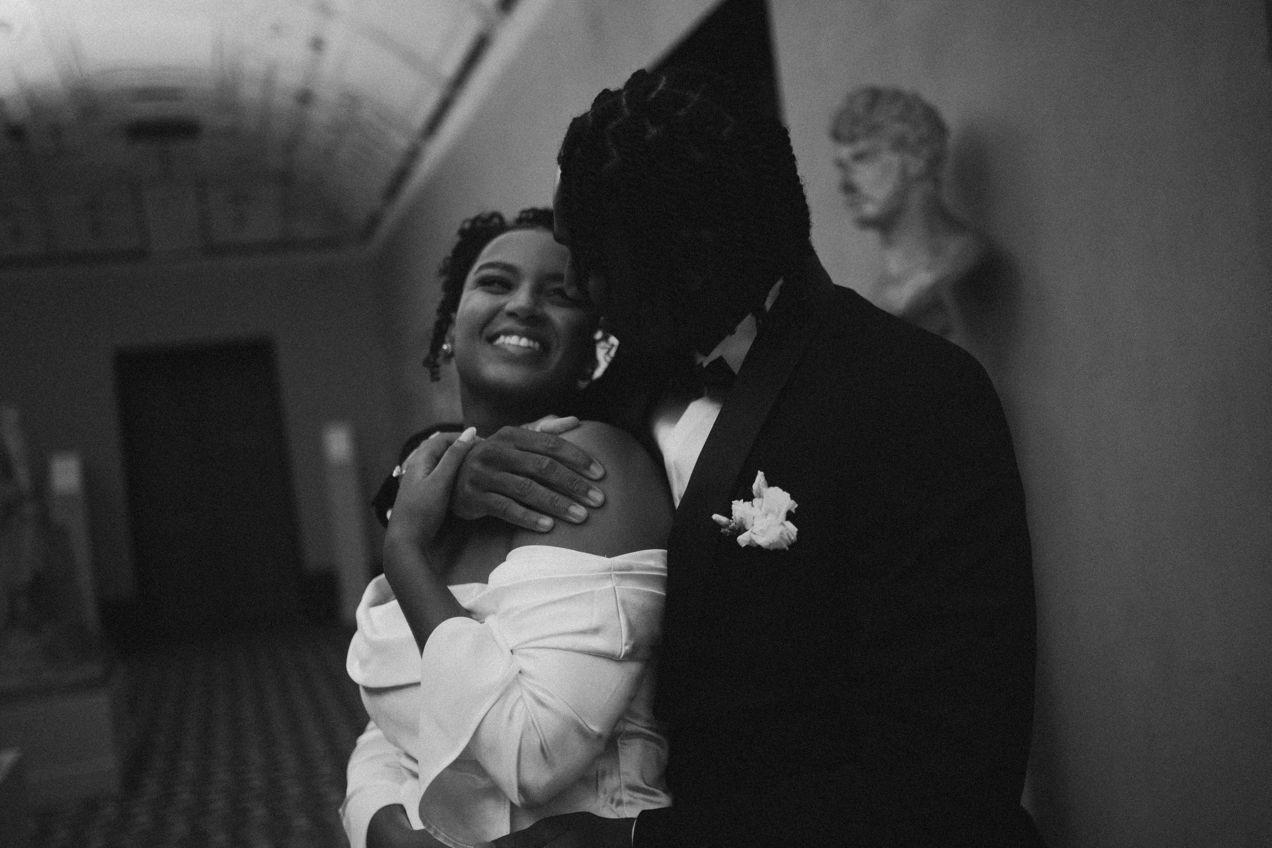 A couple dancing closely at a formal event, smiling and embracing each other in black and white.