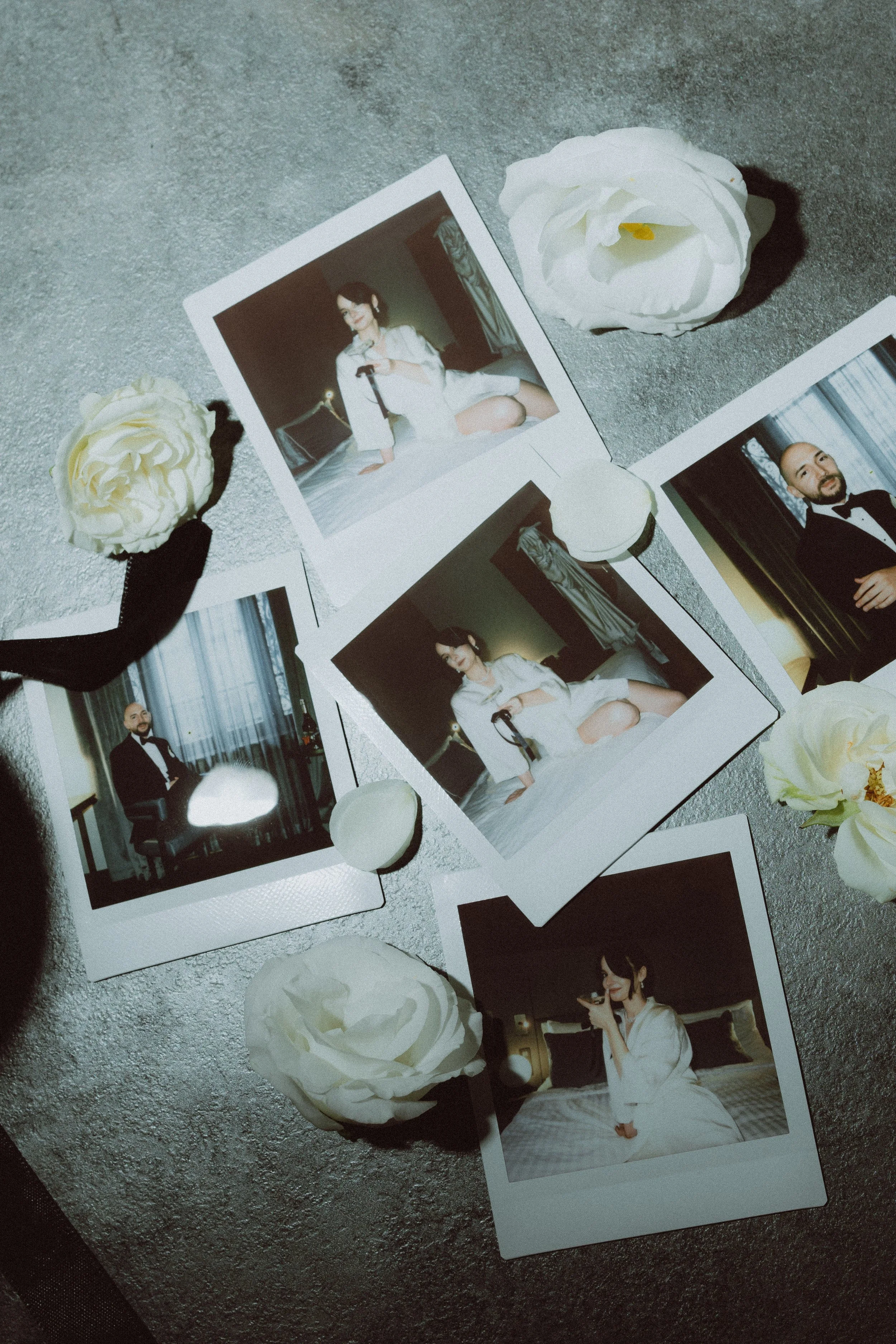 Three film photographs of a woman and a man placed on a textured gray surface, with white flowers and egg-shaped objects around them.
