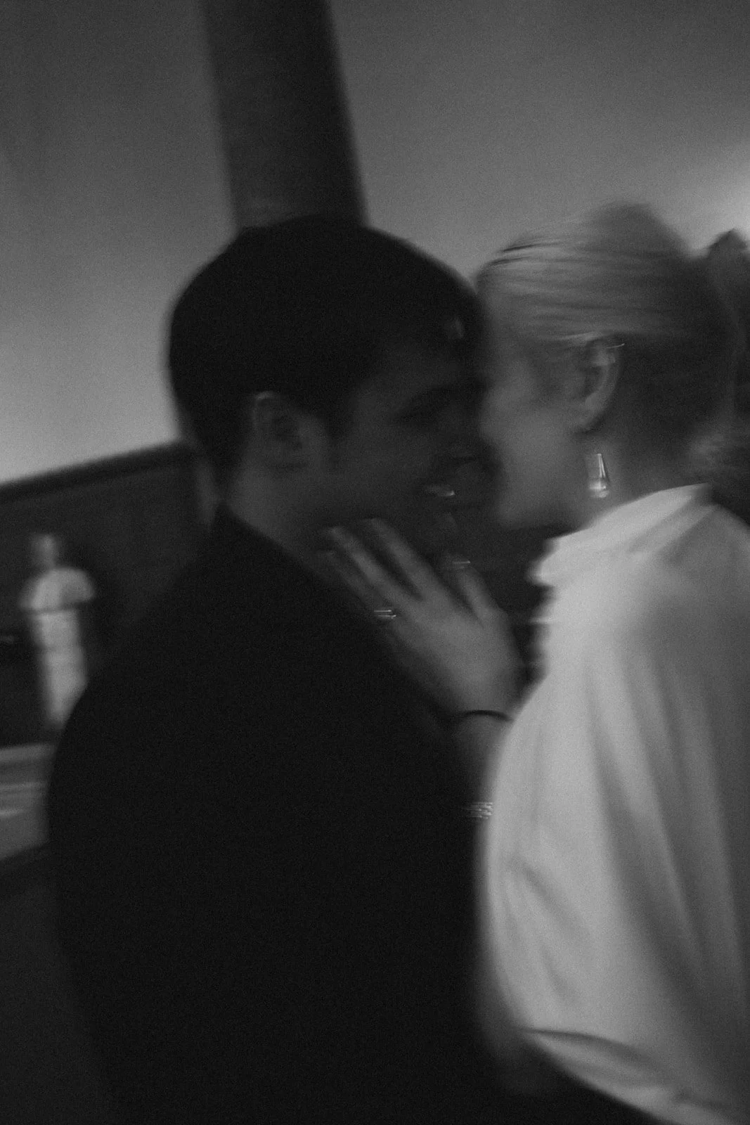 A black-and-white photo of a man and woman close together, smiling, in an indoor setting.