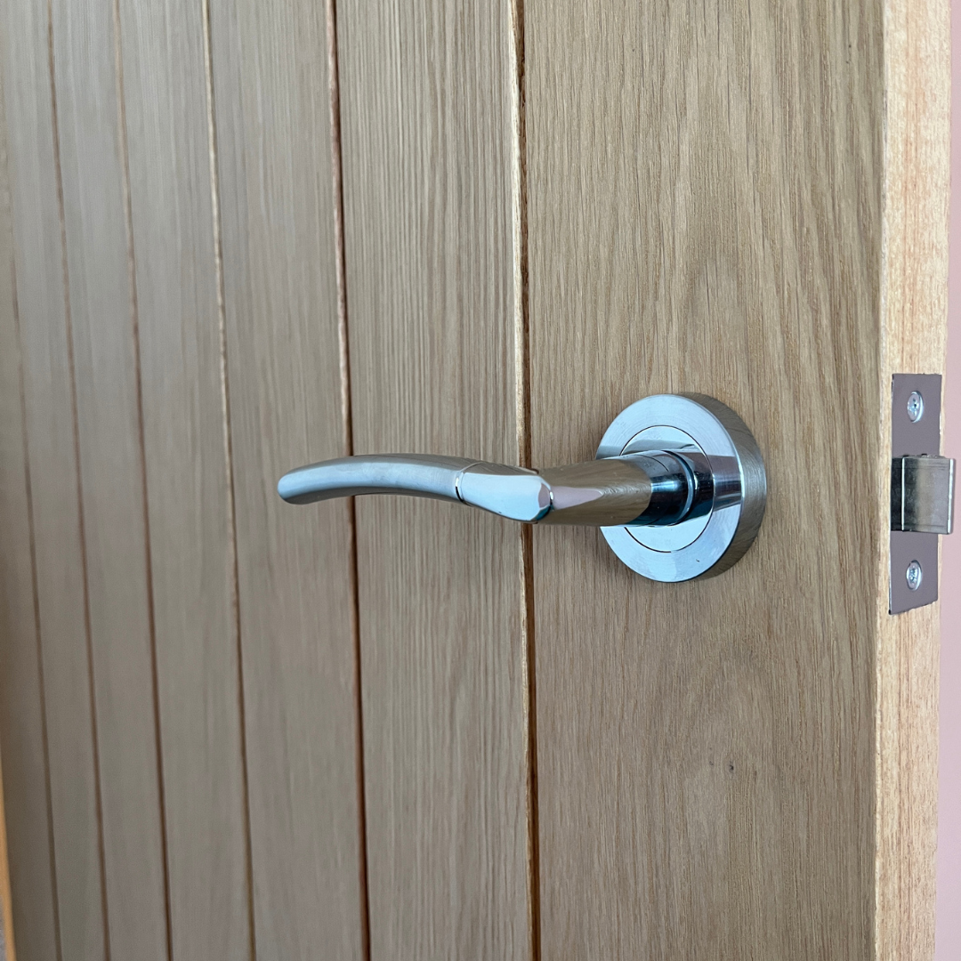 Close-up of a silver door handle on a wooden door.