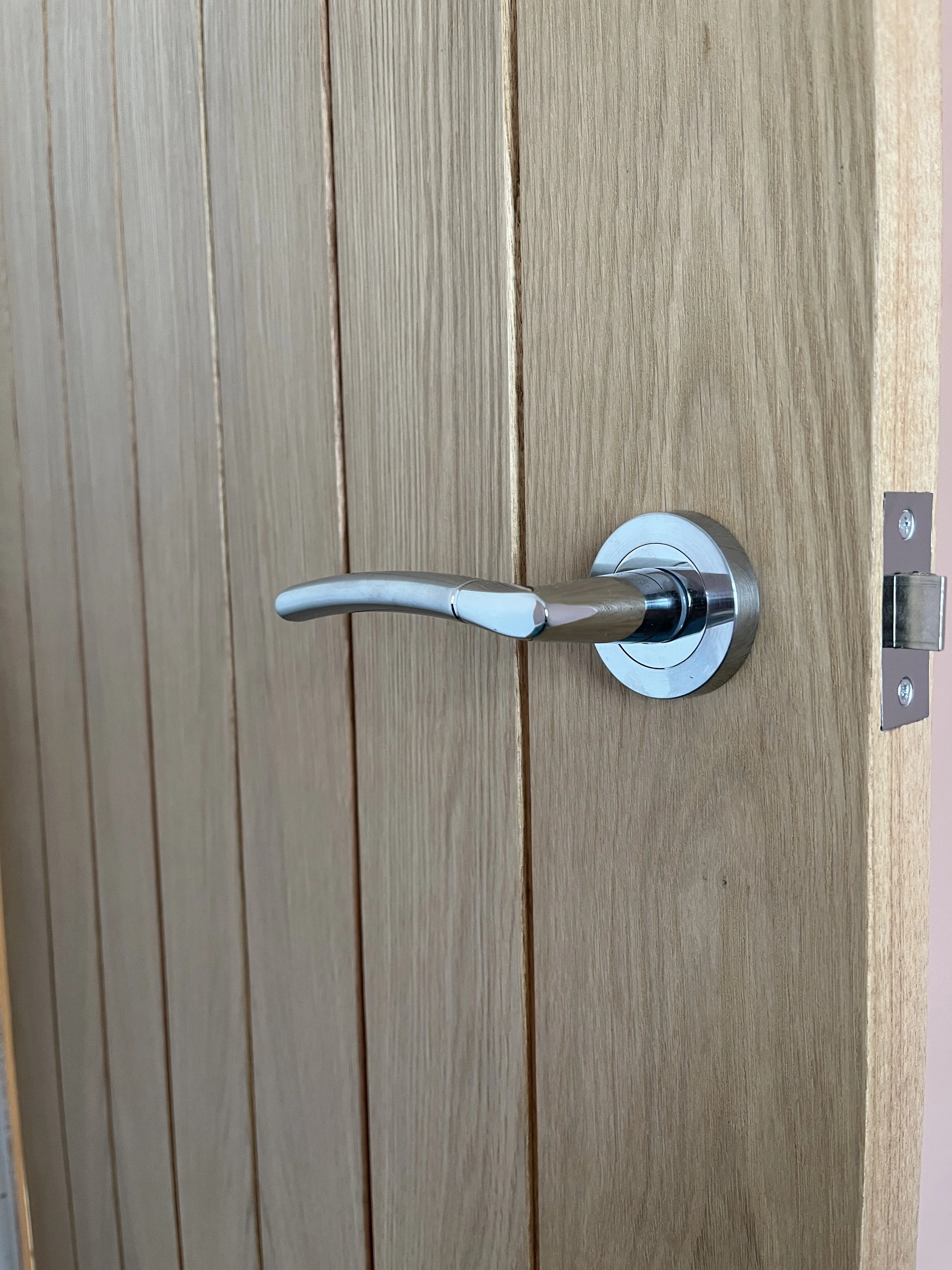 A wooden door with a silver door handle and a lock mechanism.