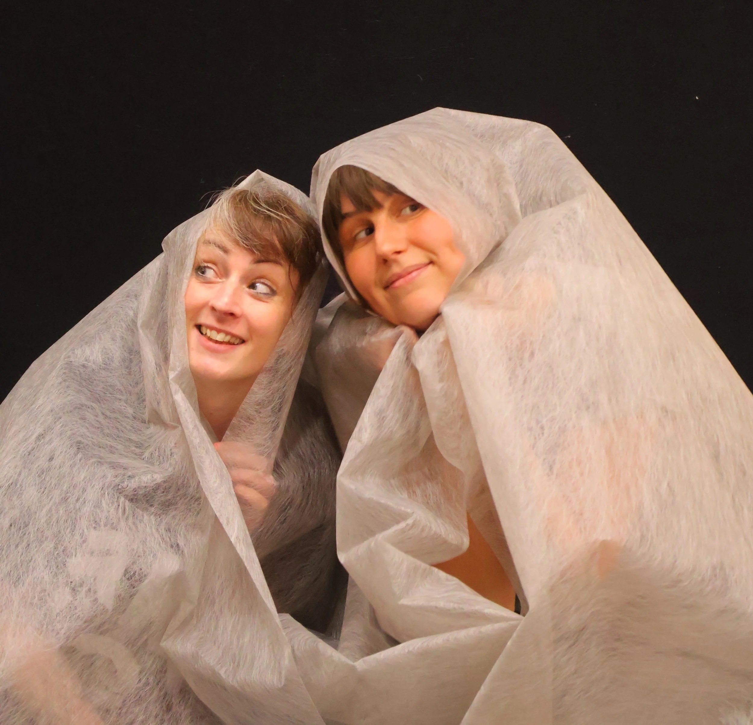 emily and miranda peeping out underneath some cloth