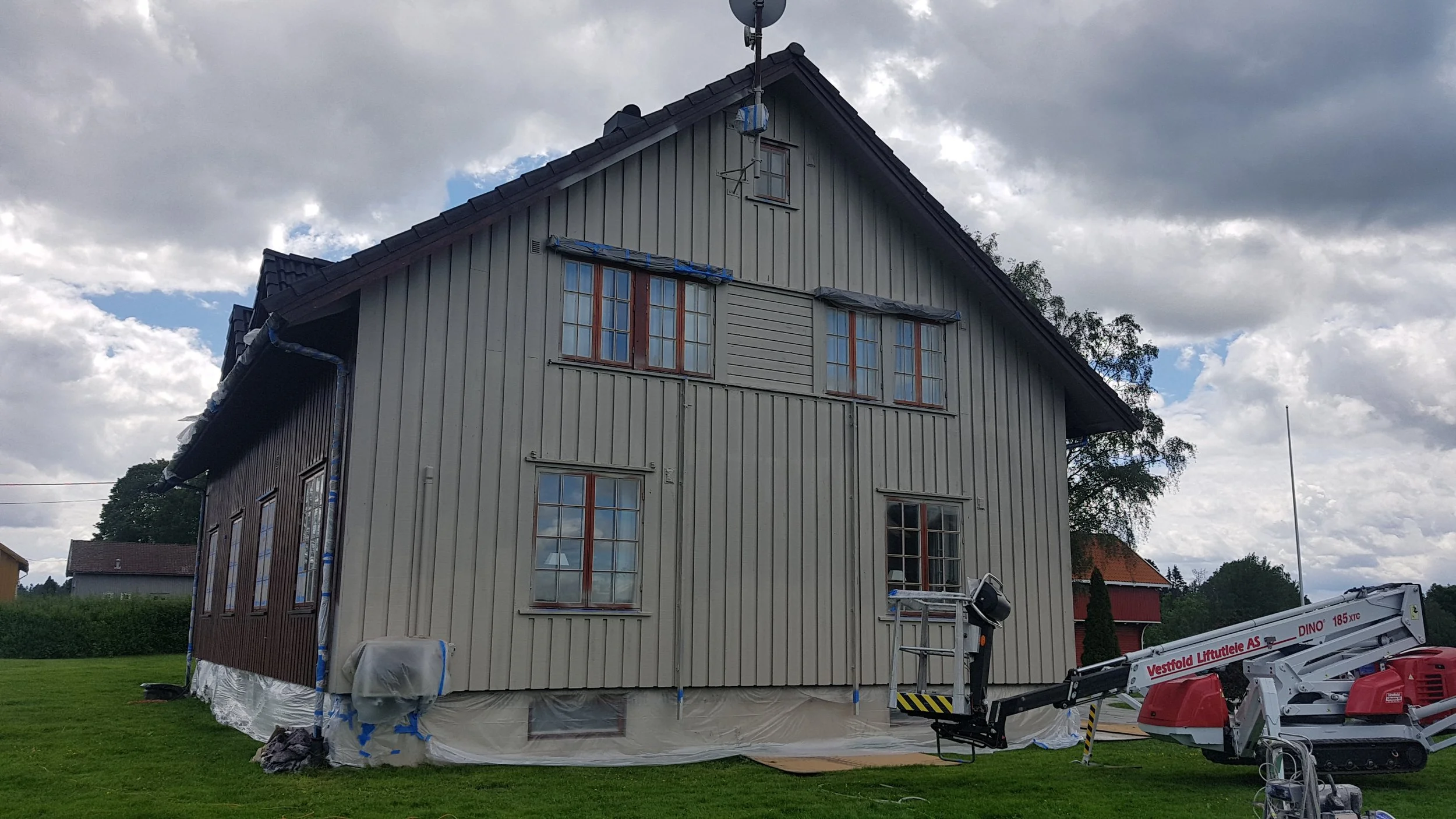 Et hus under bygging med arbeidsutstyr og stillas rundt. Været er overskyet med noen åpne områder i himmelen.