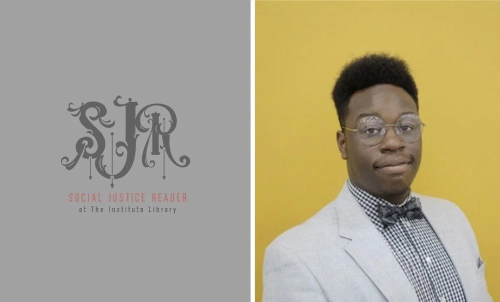 A young man in a light gray blazer, checkered shirt, and bow tie, wearing clear glasses, posing against a yellow background.