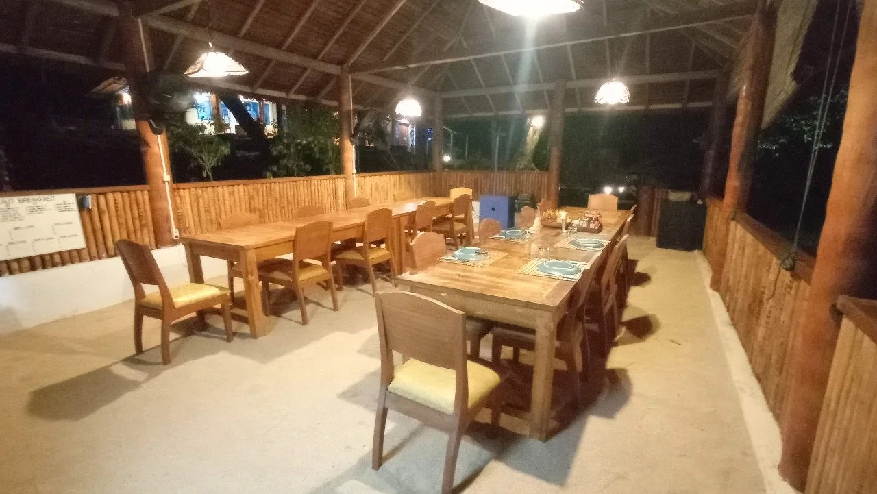 A dining room in a diving resort with woods, ratans walls and furnitures combined, and a roof made of bamboo leaves.