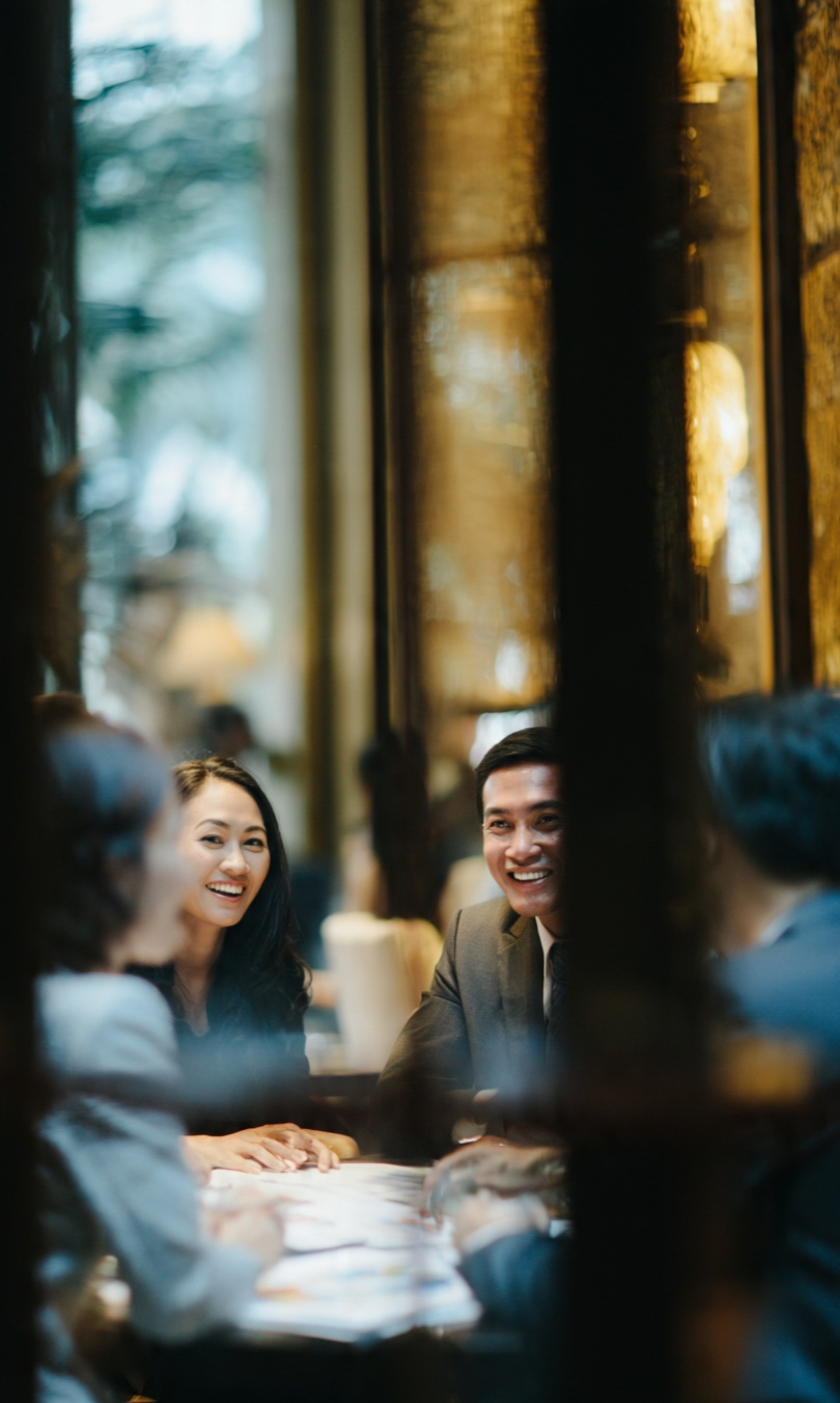 A candid photograph of four people wearing suits having a nice business conversation taken from far.