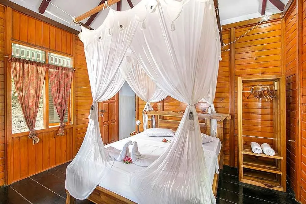 A bedroom of a diving resort house, honeymoon setting with two towels made like lovebirds.