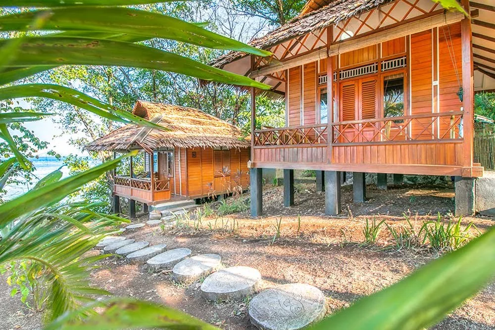 A view of two small traditional wooden house villas on a shoreline.
