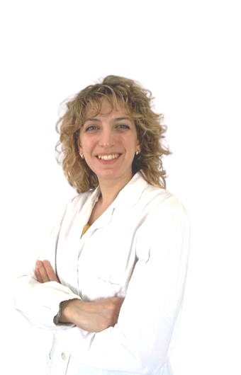A woman with curly blonde hair wearing a white lab coat, smiling with her arms crossed.