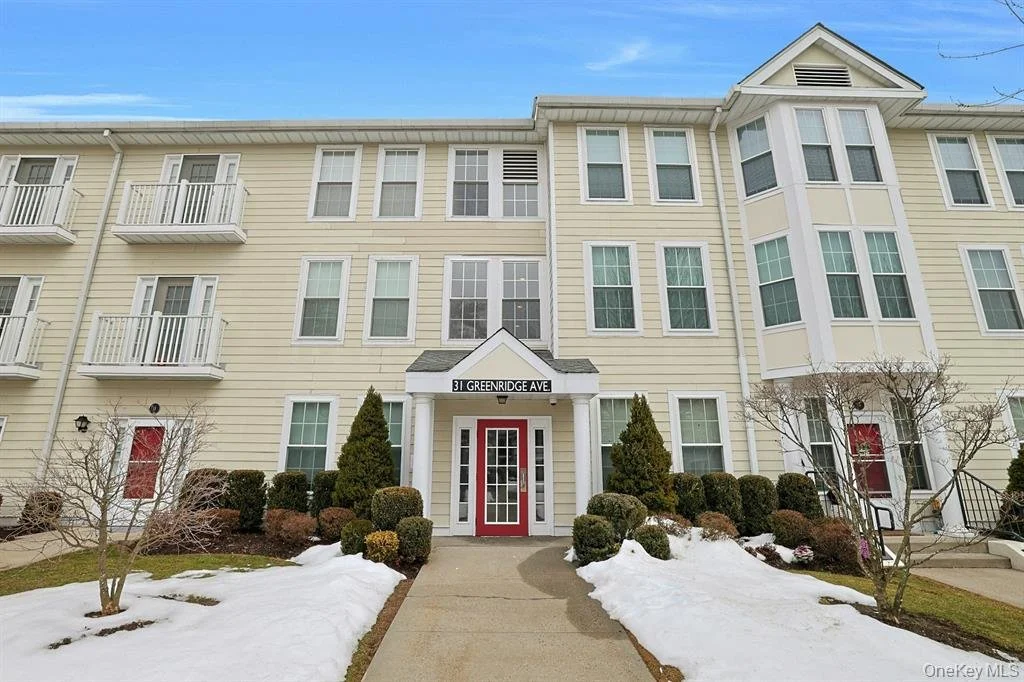 Multi-story beige apartment building with white trim, red doors, and snow on the ground, located on Greenridge Ave.