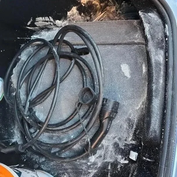 De kofferbak van een Tesla model 3 waar een emmer witte verf is in gemorst.