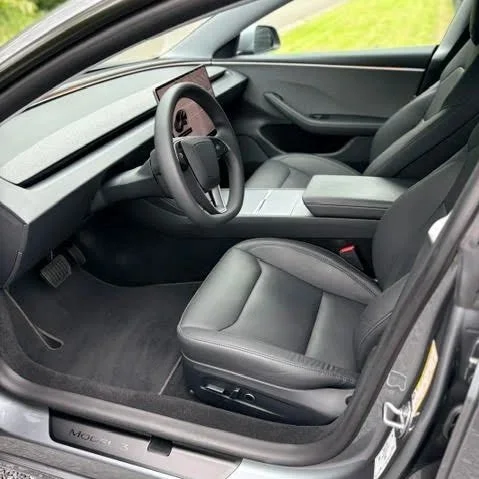 Interieur van een moderne auto met een stuur, bestuurdersstoel en dashboard in grijs en zwart kleuren.