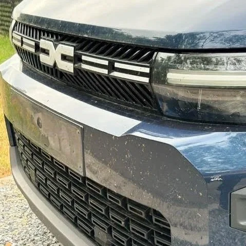 Voorzijde van een Dacia auto, met grille en hoofdlichten.