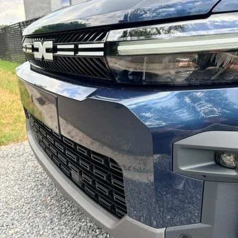 Close-up van de voorkant van een blauwe auto met duidelijk zichtbare koplampen en grille.