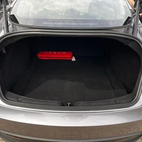 De open kofferbak van een Tesla auto met een rode Tesla bandenreparatieset erin.