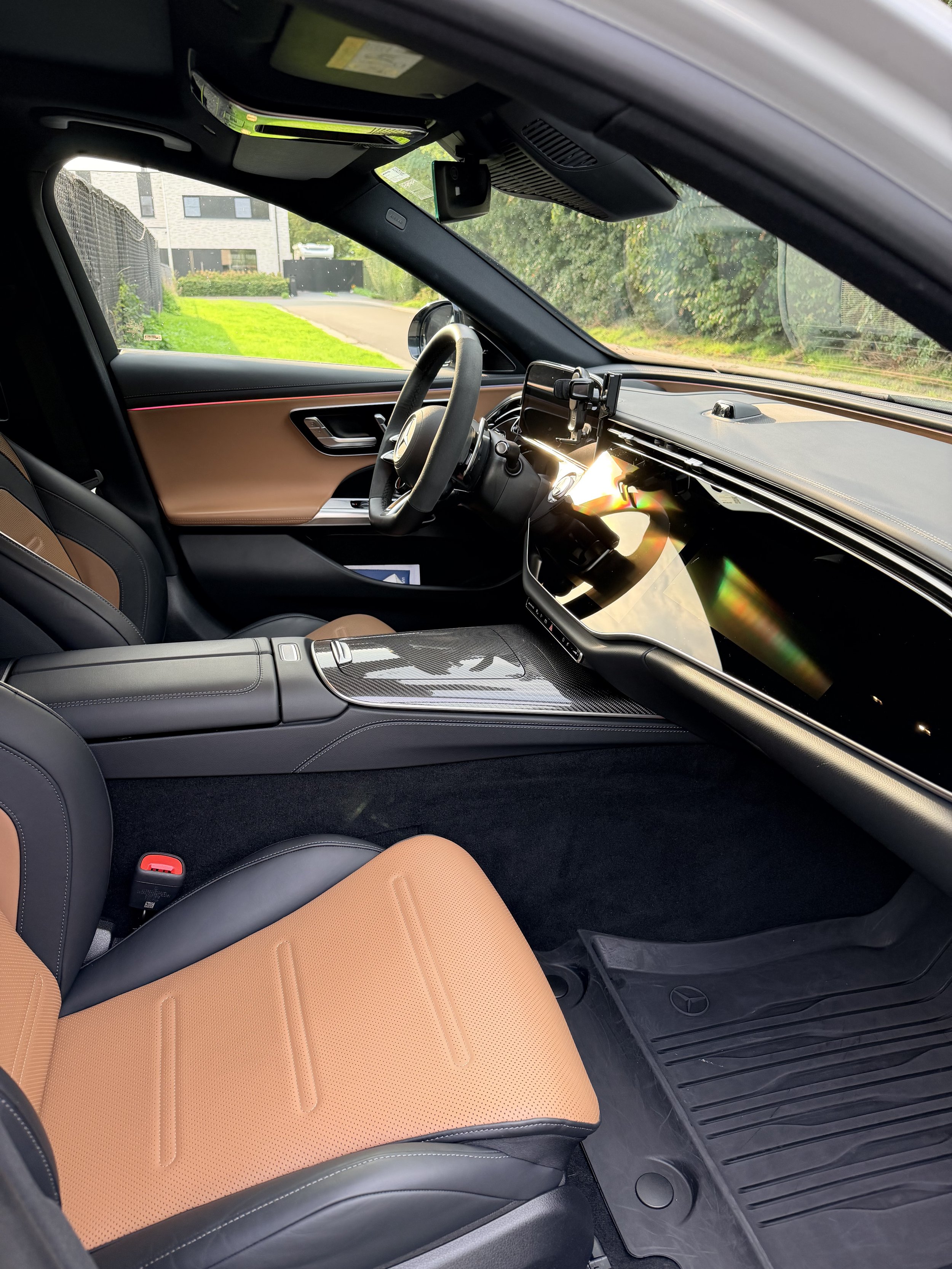 Interieur van een Mercedes E 53 AMG auto met zwart en bruin lederen stoel en een dashboard met een groot scherm.
