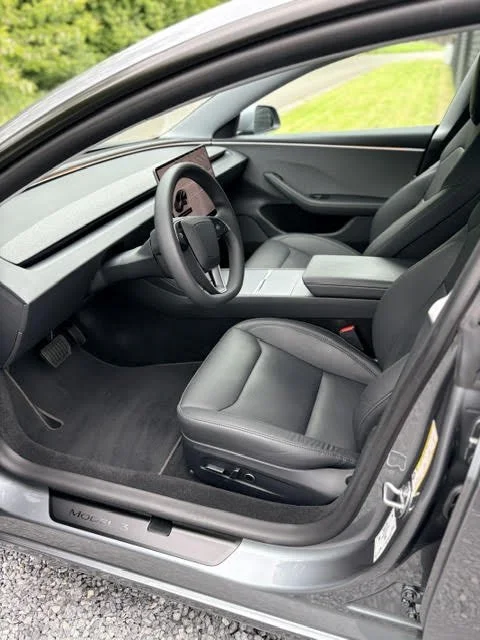 Interieur van een Tesla Model 3, met zwarte lederen stoelen, tweekleurig stuur en panoramisch dashboard